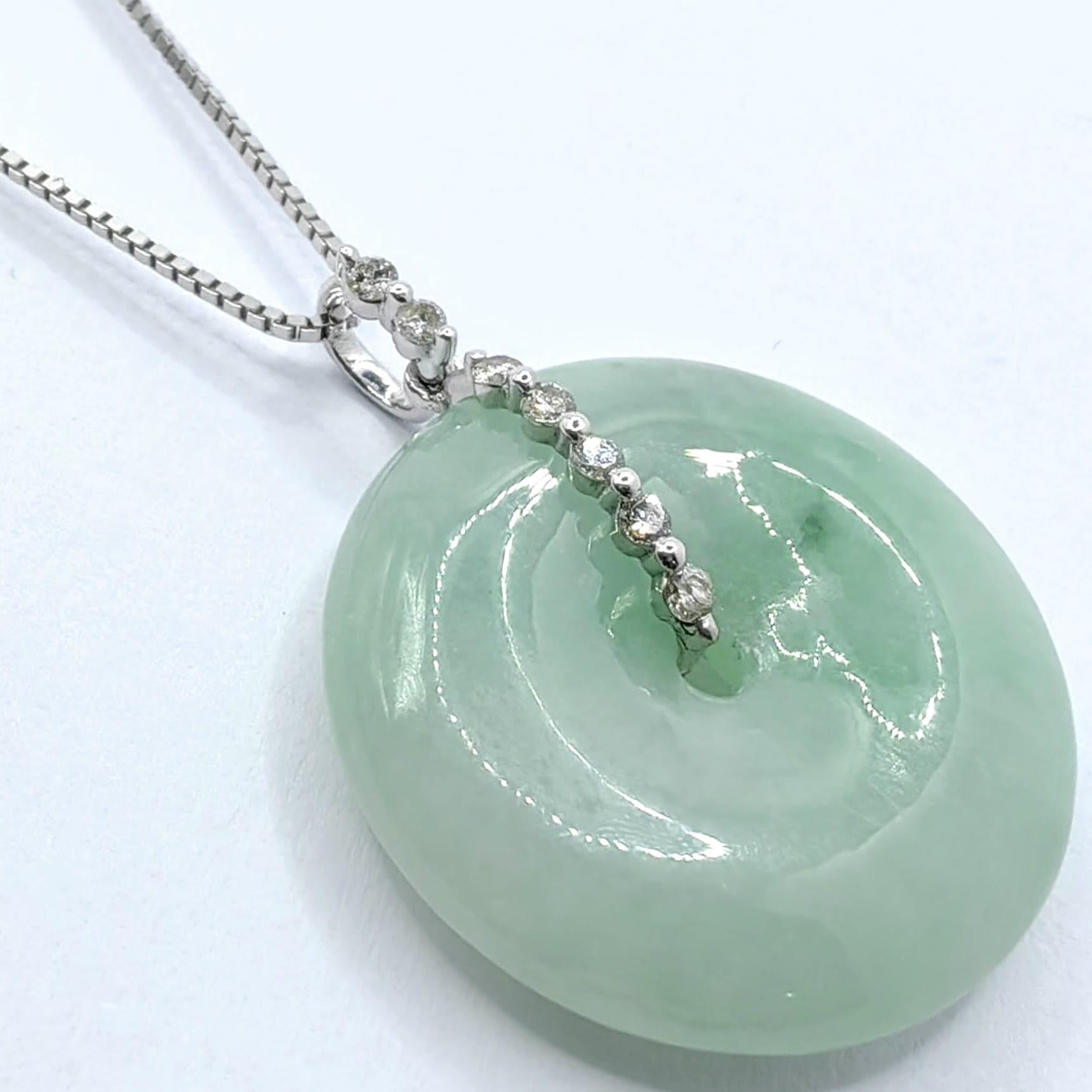 This exquisite pendant features a perfectly round disc of pale green jadeite, showcasing the stone's natural beauty and serene translucency. The jade displays a delicate mint green hue with subtle natural variations that bring unique character and