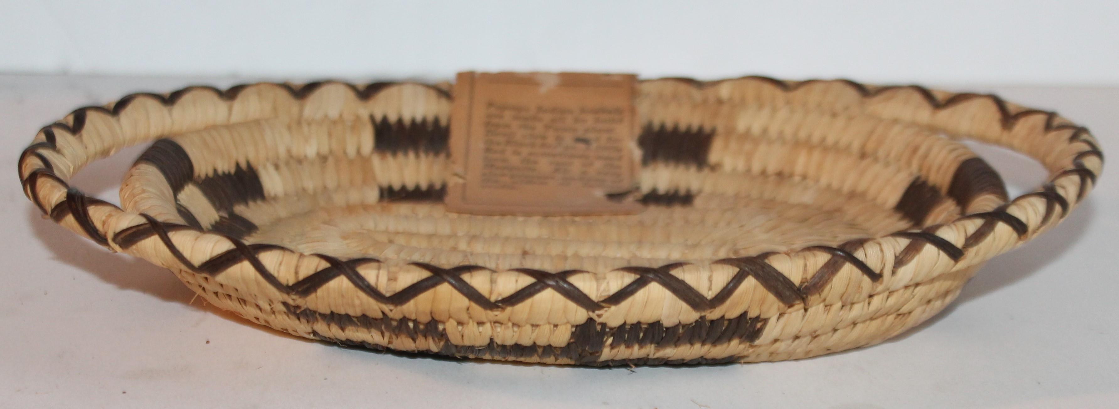 This fine mini Papago Indian basket is a small tray with handles in fine condition. These baskets are made from the yucca plant. Devil claw is used for the black design. A little red is sometimes used from the root of the mesquite. Ali a very slow
