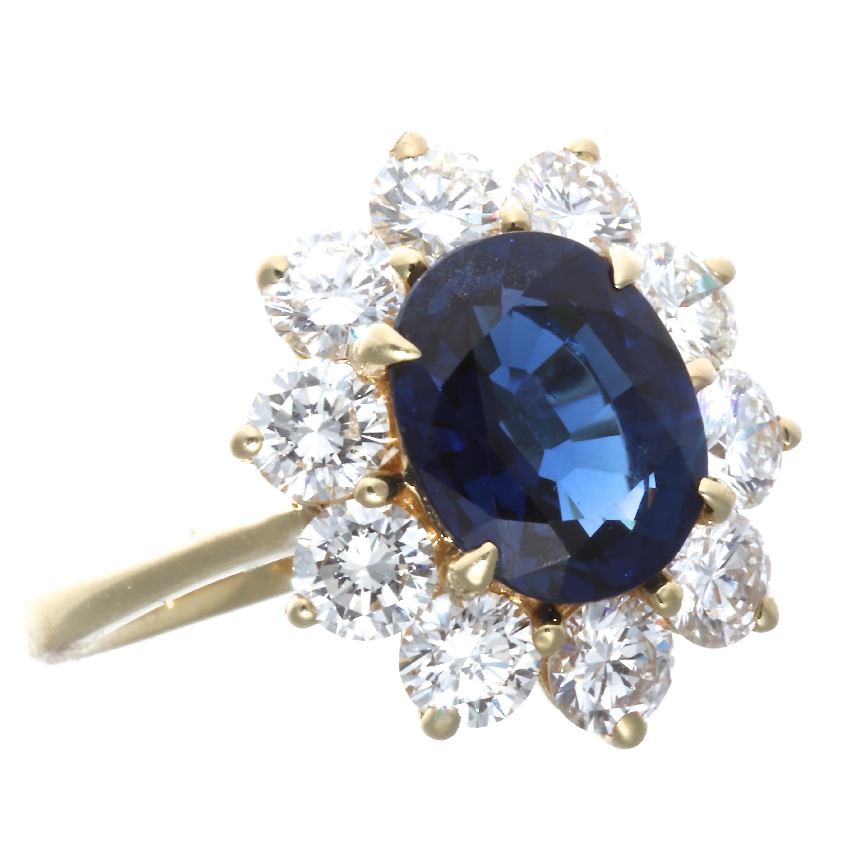 This classic cluster ring features an AIGS Thai heated Royal Blue 3.08 carat sapphire center. It is surrounded by 10 diamonds that weigh approximately 1.50 carats, graded H-I color, VS+ clarity. Circa 1990's. Stamped 18k. Ring size 7 and comes with