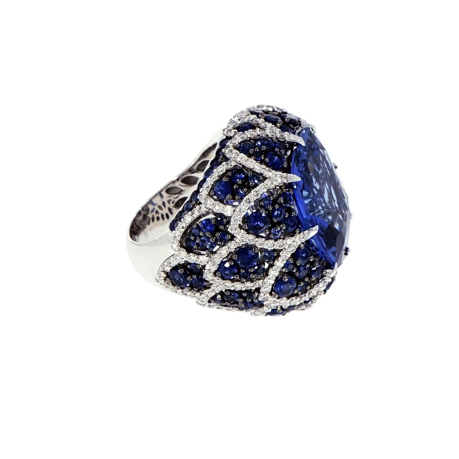 Inspired by the history and beauty of the Mediterranean with a modern twist of fashion forward jewelry.
This gorgeous Sapphire and Diamond cocktail Ring is handcrafted in 18K White Gold. 
Centering the ring is a gorgeous Certified 18.23 carat Blue