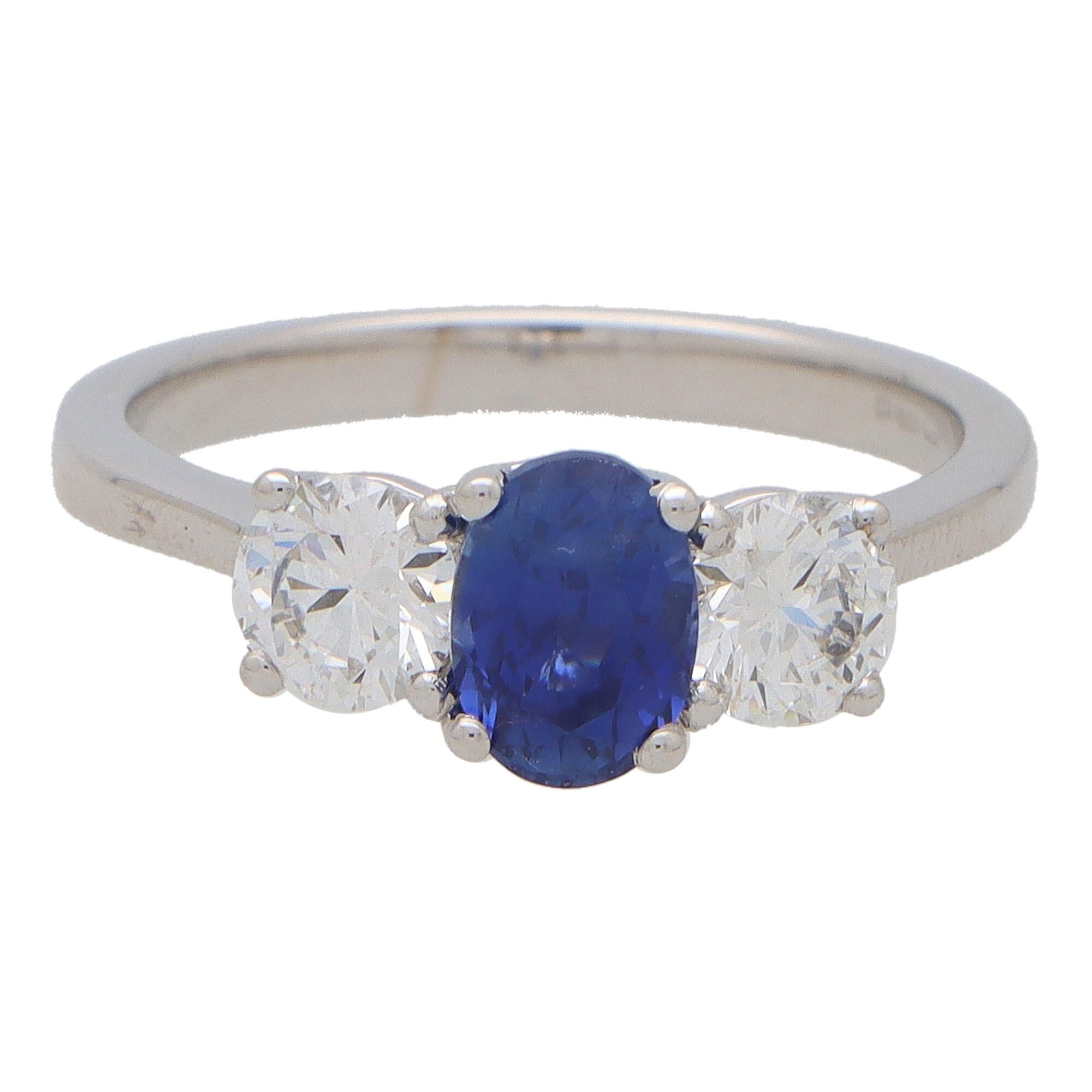  A truly stunning certified sapphire and diamond trilogy ring set in 18k white gold.

This classic three stone ring is centrally set with a 1.29 carat oval blue sapphire which is four claw set in an open back triple setting. The sapphire is then
