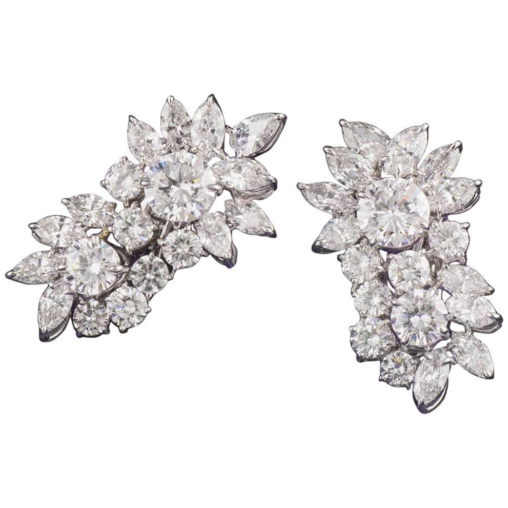 A pair of decadent diamond cluster earrings in platinum. Each earring is composed of a cluster design encompassing a mixture of round brilliant cut, pear cut and marquise cut diamonds. The first earring is comprised of a 2.06ct and a 1.01ct round