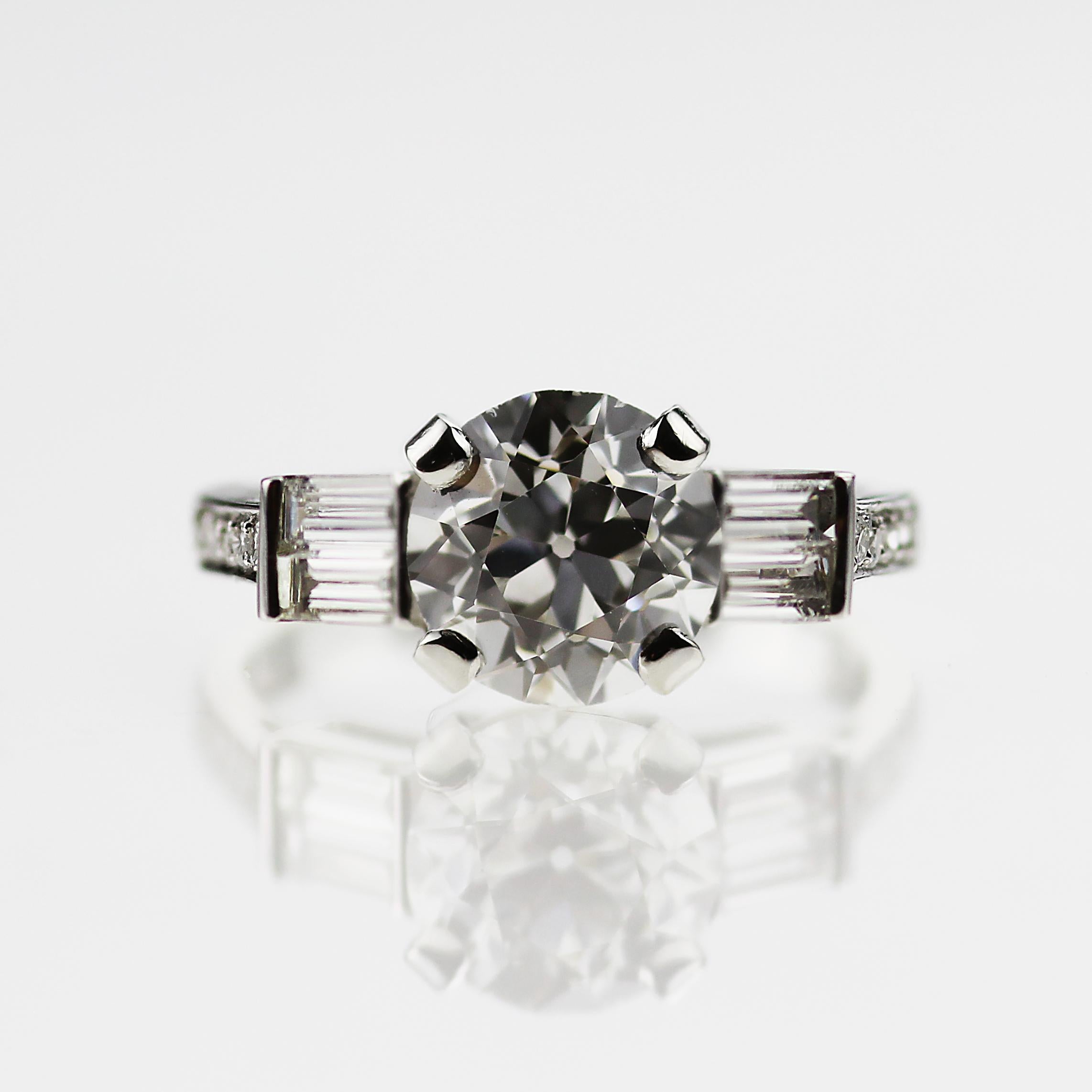 An elegant platinum and diamond solitaire ring with baguette diamond shoulders. The Old European cut diamond dates to c.1910 and has been reset in a modern ring mount, adding a contemporary touch to a classic. The platinum band is stamped with