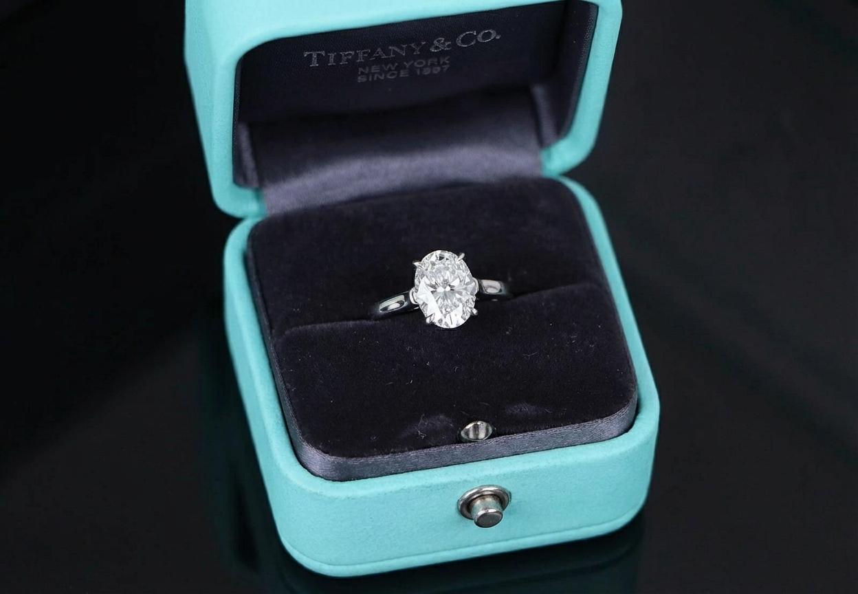 Cette bague en platine certifiée Tiffany & Co. est ornée d'un superbe diamant ovale brillant de 2 carats, alliant des proportions élégantes à une brillance exceptionnelle. Le diamant est de couleur G, offrant une apparence brillante et presque