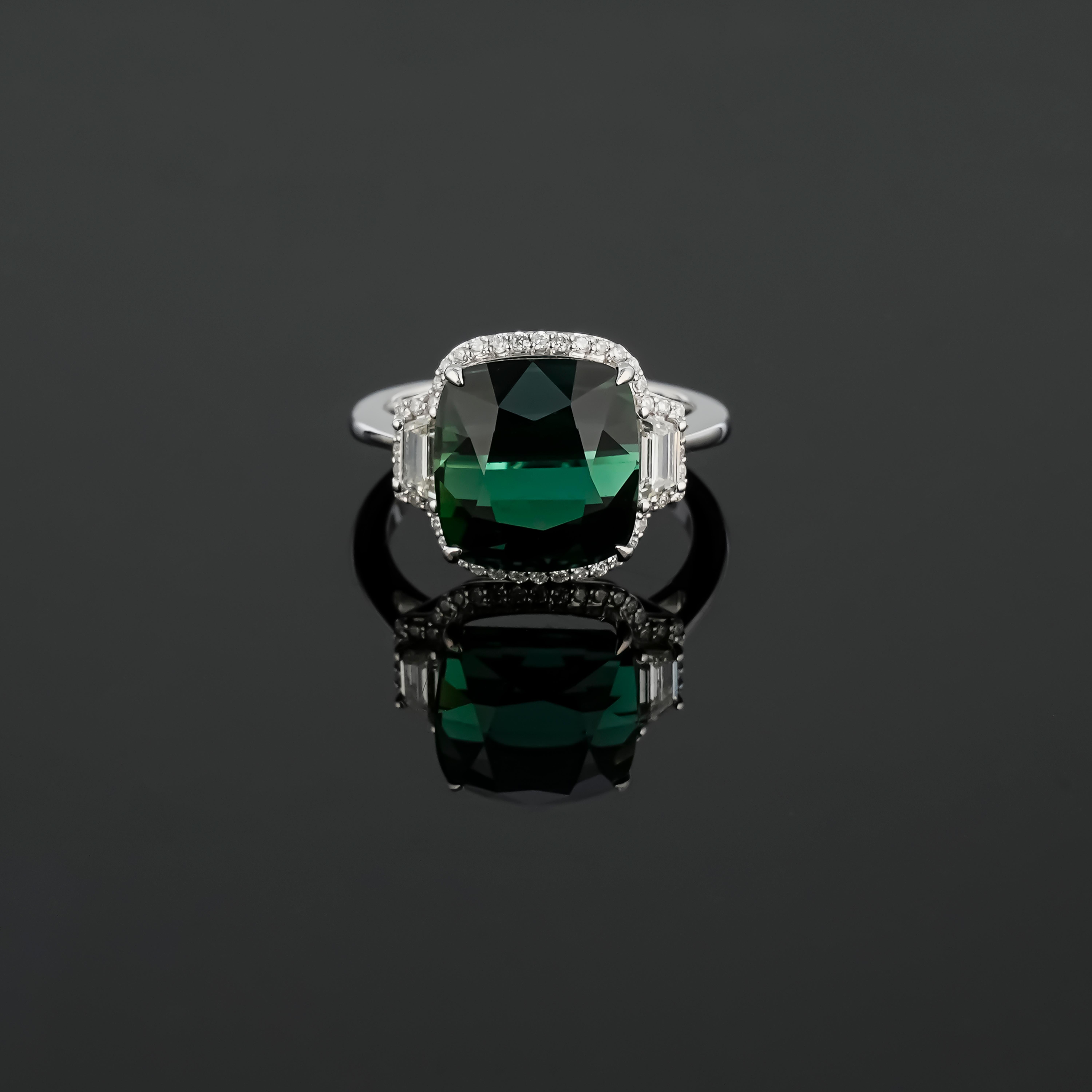 
Cette bague de cocktail élégante et simple est ornée d'une tourmaline de 9,26 carats à taille coussin, de pierres latérales en diamant trapézoïdal de 0,37 carat et de diamants de 0,26 carat à taille brillant, le tout serti dans de l'or blanc et de