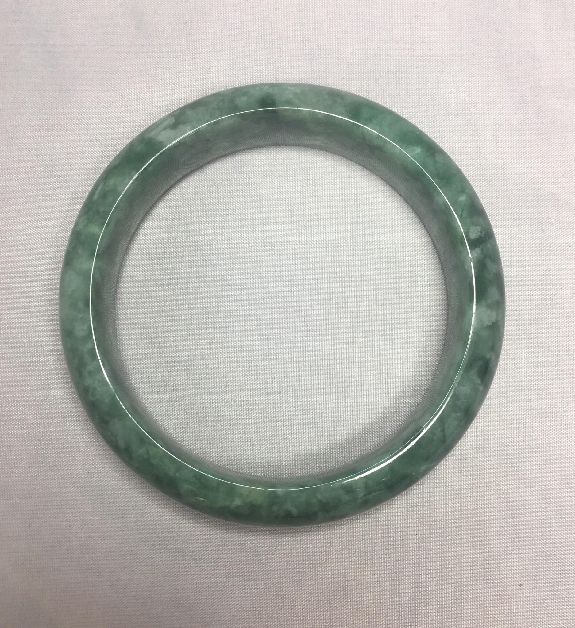 Beautiful natural and untreated jadeite jade bangle.

Has a beautiful mottled green colour, and an excellent polish and lustre with no cracks or chips.

Comes with a Gemmological Consultancy Certificate confirming the piece as natural and untreated