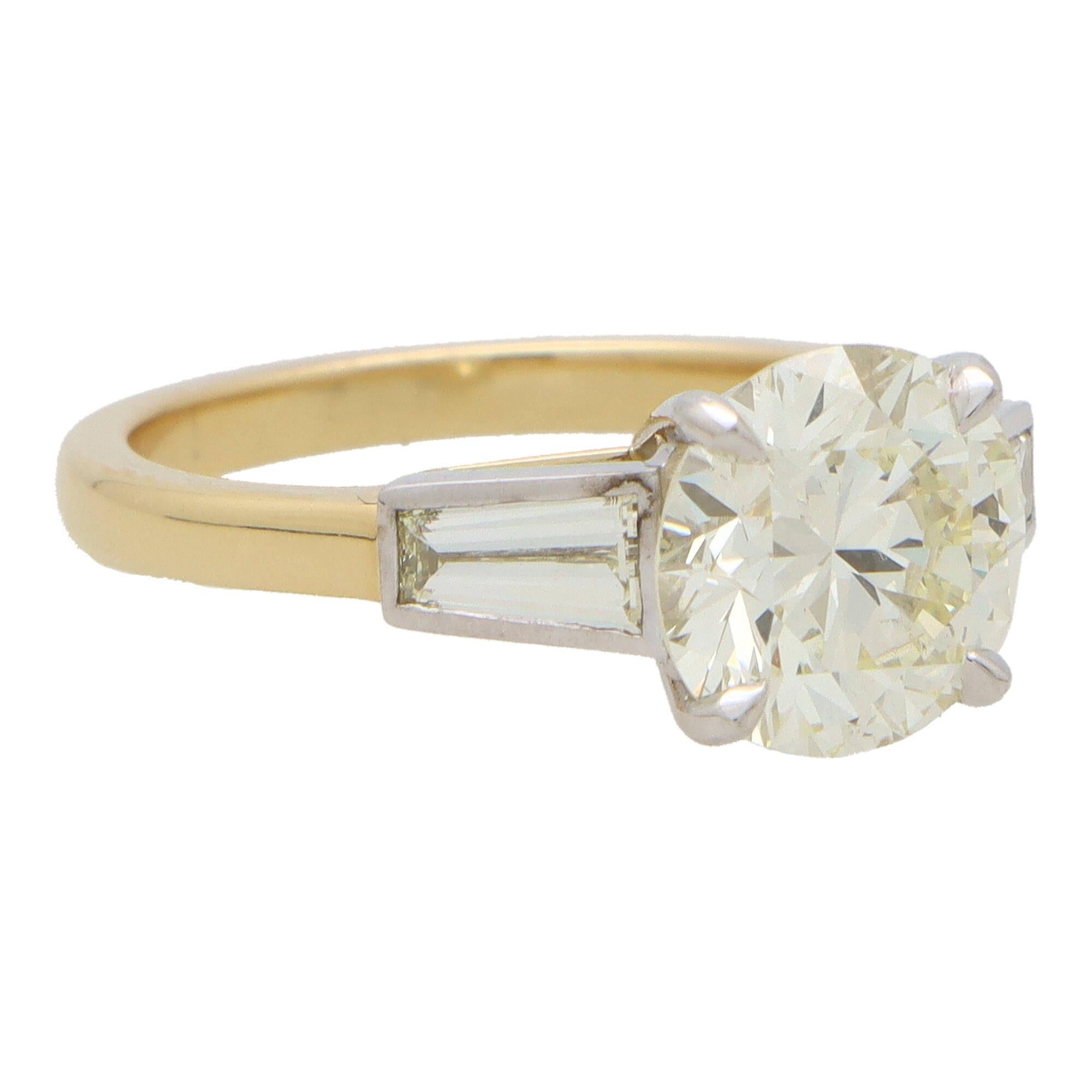 A beautiful certified vintage round brilliant cut diamond three stone ring set in 18k yellow gold and platinum.

The piece is centrally set with a sparkly 2.56 carat round brilliant cut diamond which is securely 4 claw set. To either side of the