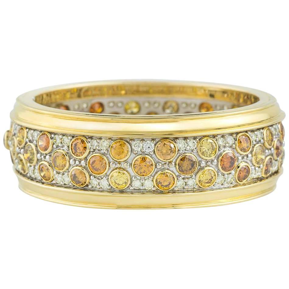 A beautiful 18k white and yellow gold diamond bangle. The bangle is set with 59 round brilliant cut coloured diamonds in a rubover setting placed around the bangle. These coloured diamonds have a total diamond weight of approximately 21.12ct, with