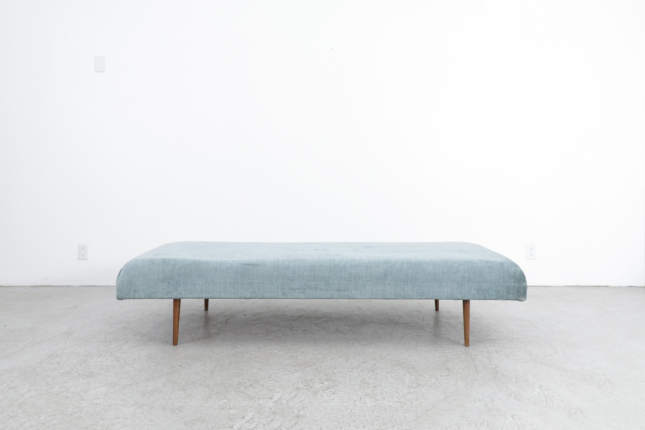 Elegant Mid-Century Swedish daybed featuring misty blue velvet upholstery and tapered solid teak legs. The silhouette is clean and modern, with subtly sloped corners that reveal the only visible stitching—adding just the right amount of tailored
