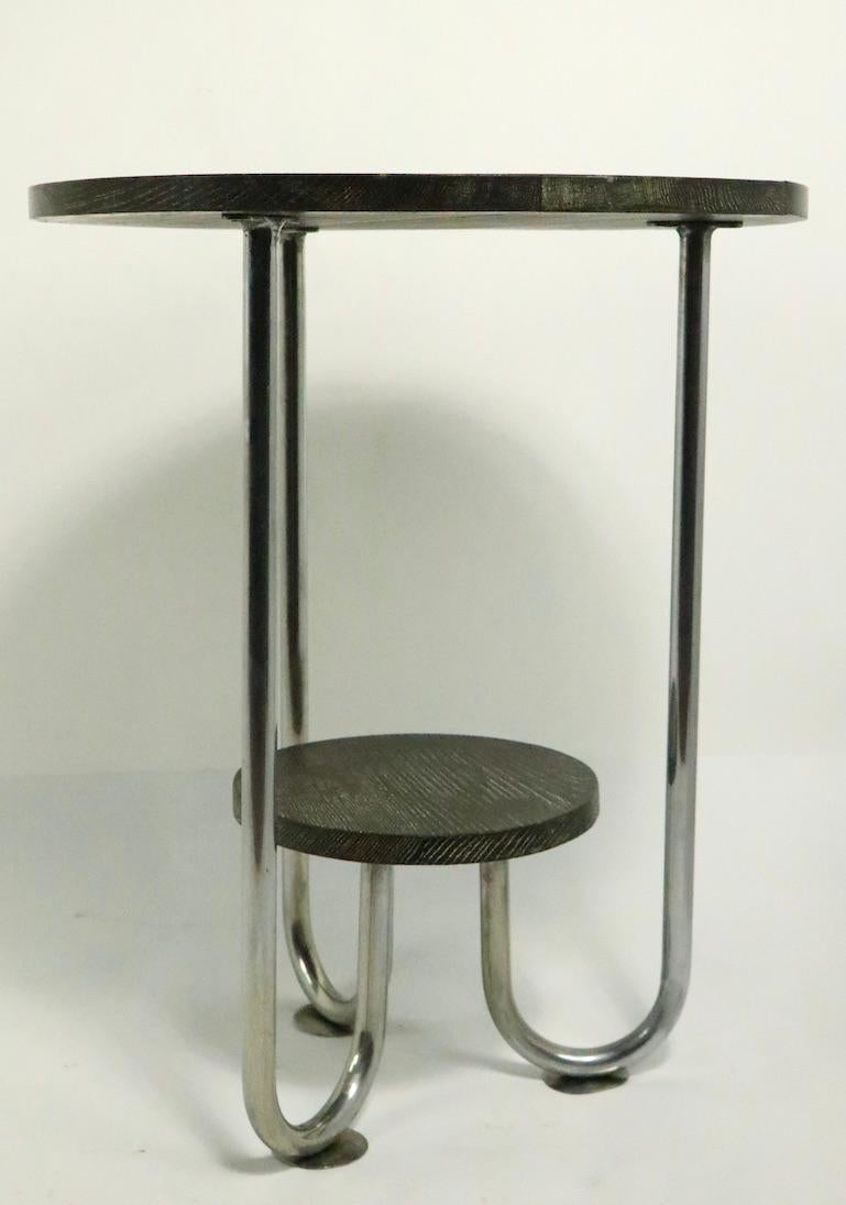 Stylish Machine Age, Art Deco chrome and oak table, probably English, in the style of Wolfgang Hoffmann. This stand has a 24 inch diameter circular top, with a smaller 13 inch diameter lower shelf. The frame is of heavy chrome-plated tubular metal.