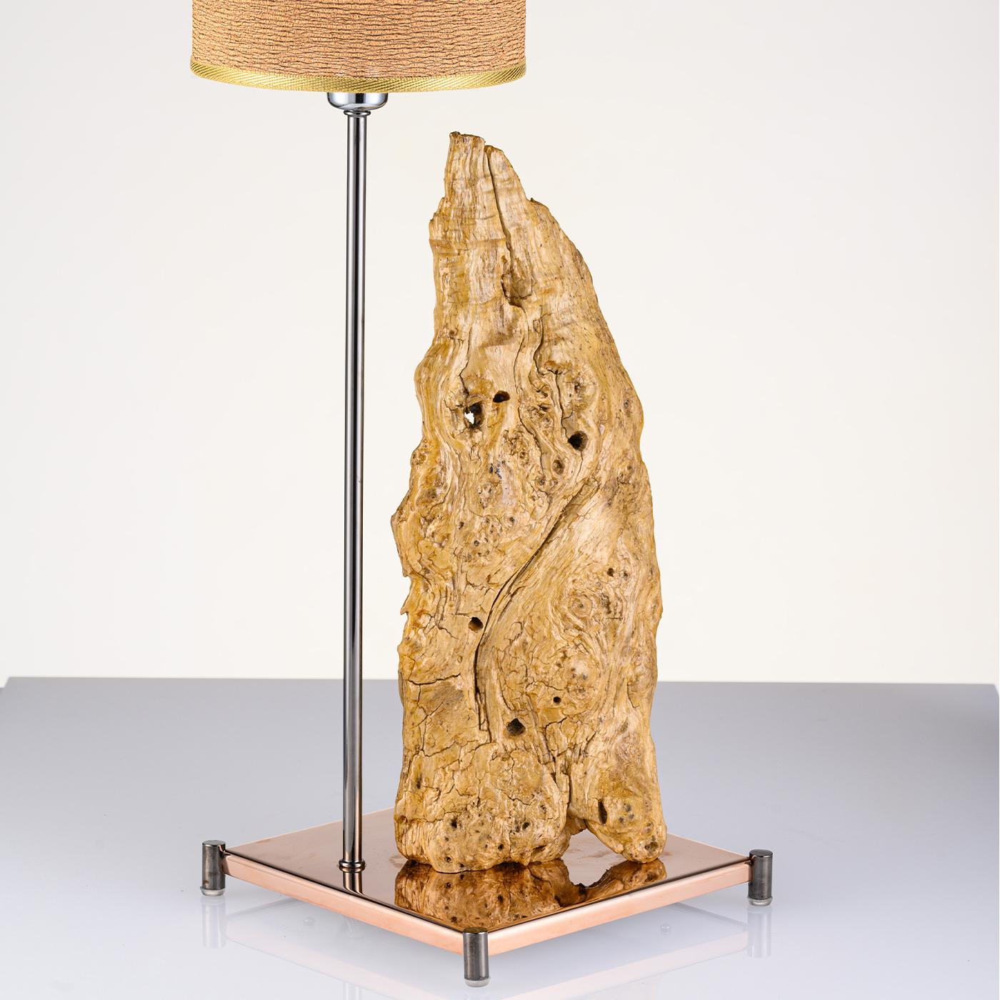 With a base in reflective rose gold stainless steel and black brass feet, the Cervino lighting sculpture features a unique piece of washed-up sea wood, generally from the Amalfi Coast, placed aside a black steel rod with fabric lampshade. Highly