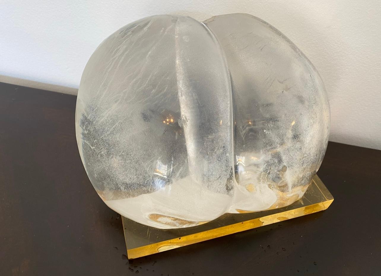 An abstract compressed clear resin sculpture on a yellow resin base suggesting a female derrière shape. Signed by the artist.