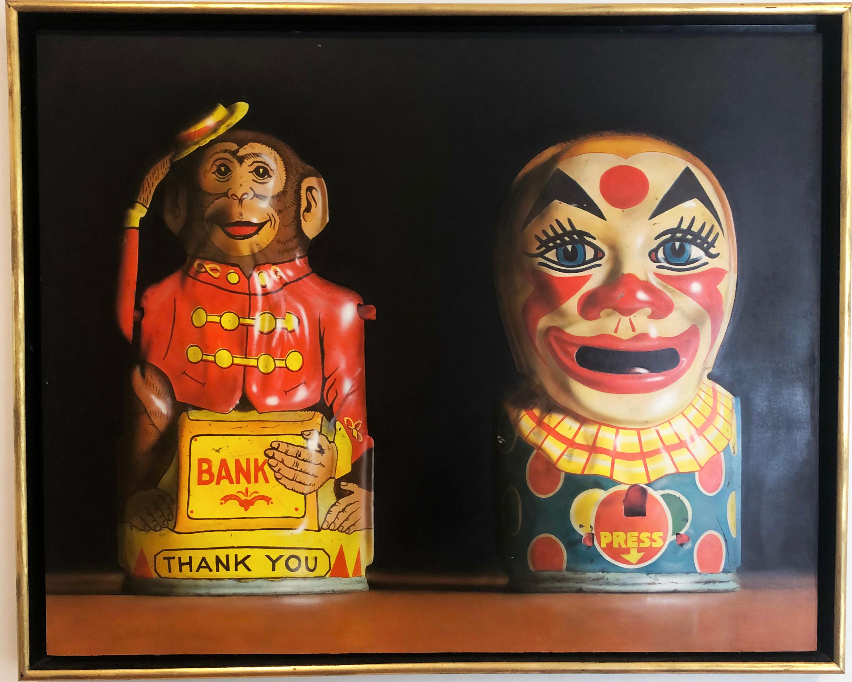 Deux banques de jouets, 1982, par l'artiste américain Cesar J. Santander. Huile sur panneau, 27.75 x 34.5 in. Ce tableau présente un singe et un clown tirelires finement détaillés dans des couleurs riches de rouge, jaune, bleu, marron et noir.