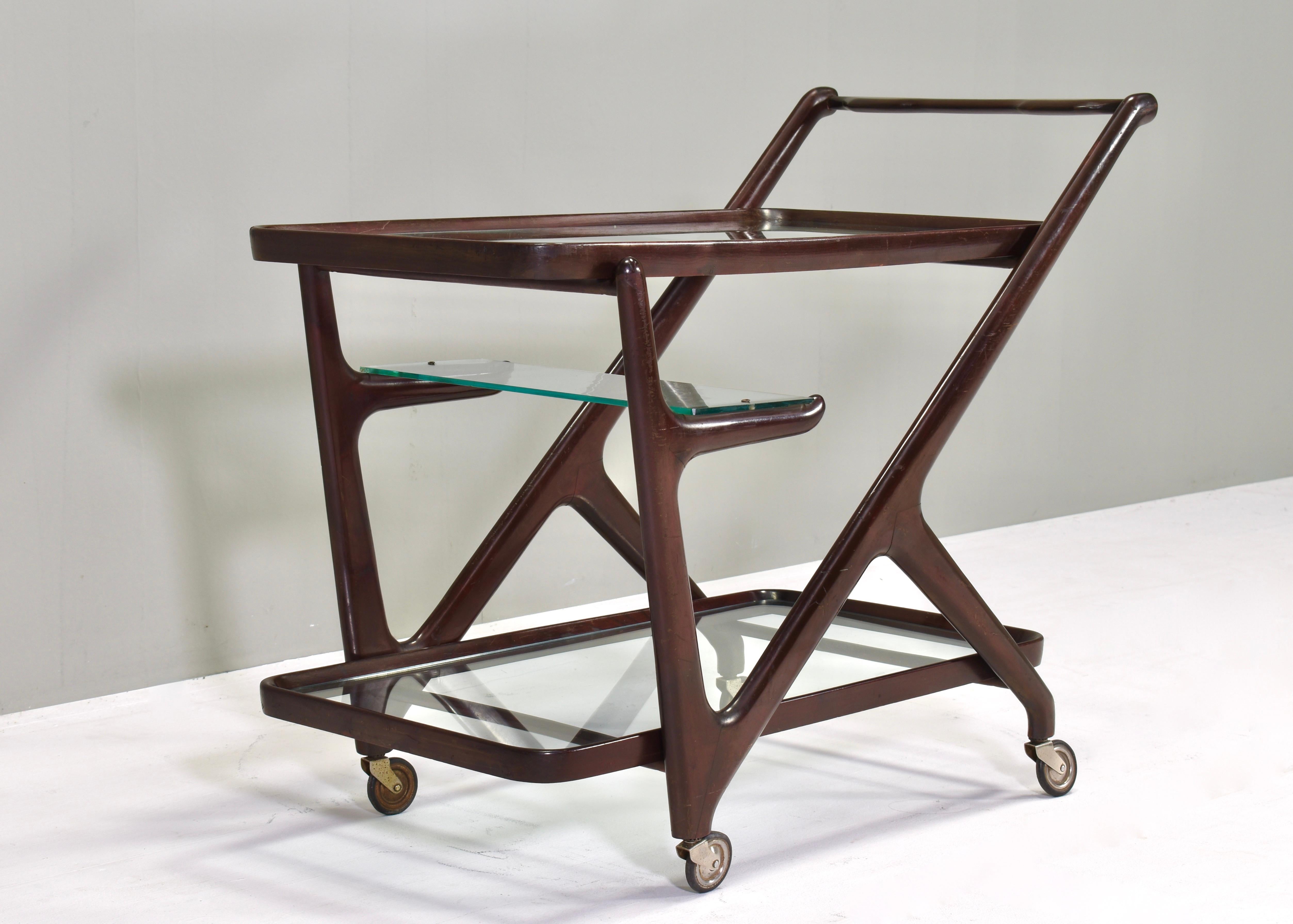 Designer: Cesare Lacca
Manufacturer:
Country: Italy
Model: Bar cart / Tea trolley / Serving cart 
Design period: 1950’s
Date of manufacturing: circa 1950
Size wdh in cm: 83x43x69 centimetre
Material: Stained wood / Glass
Condition: Fair /