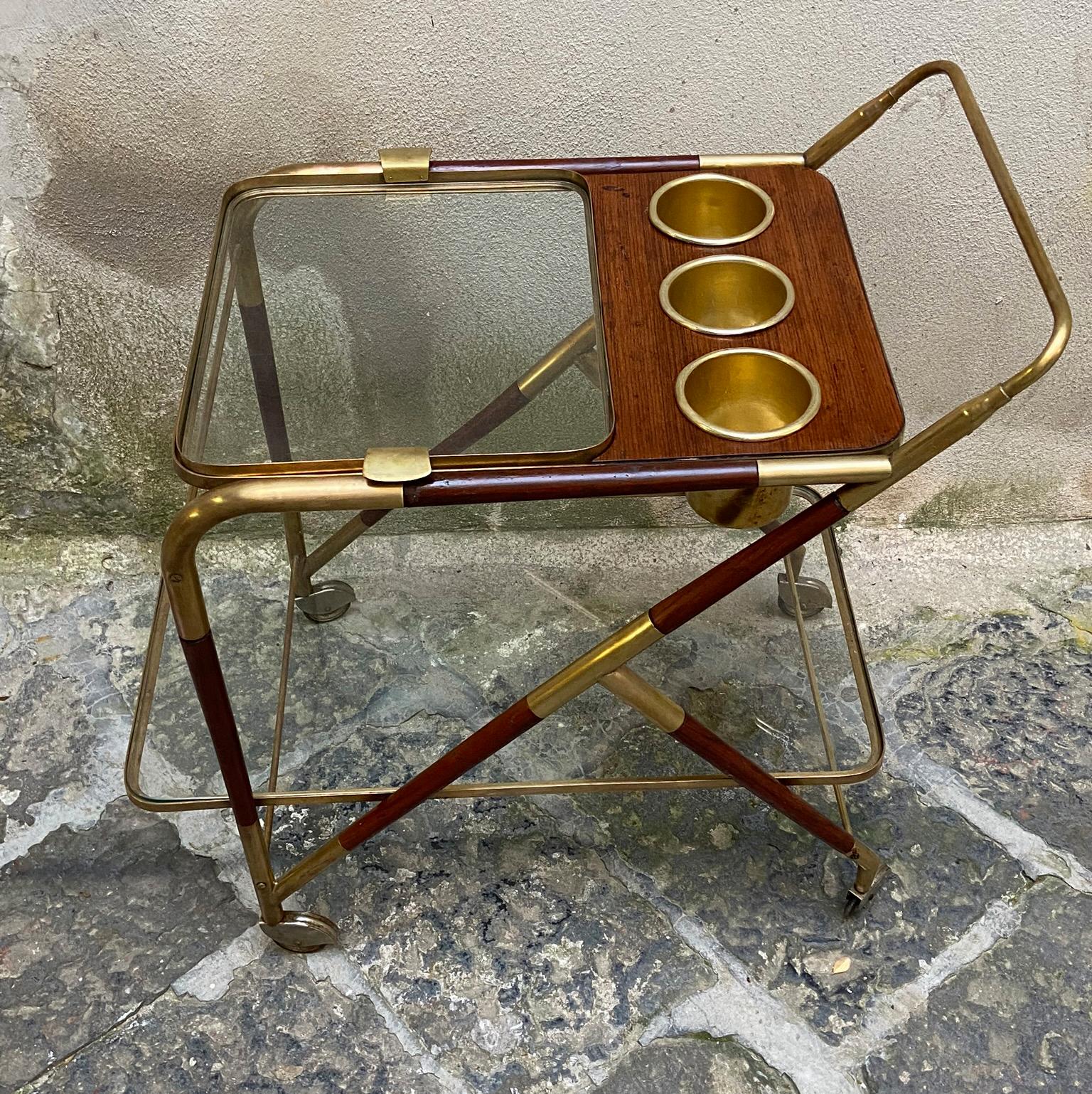 Iconic Italian vintage bar cart by Cesare Lacca featuring a dynamic structure of brass and mahogany. There are two levels, the top is a removable tray. The cart has three bottle holders as well. The casters operate smoothly.