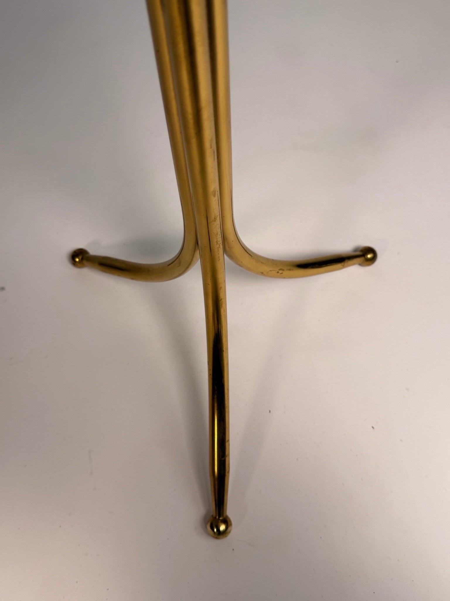 Posée et sculpturale, cette table d'appoint Cesar Lacca capture le glamour sans effort du design italien des années 1950. Un trépied en laiton massif légèrement patiné s'élève dans un gracieux évasement, coiffé d'un fleuron en forme d'anneau, et