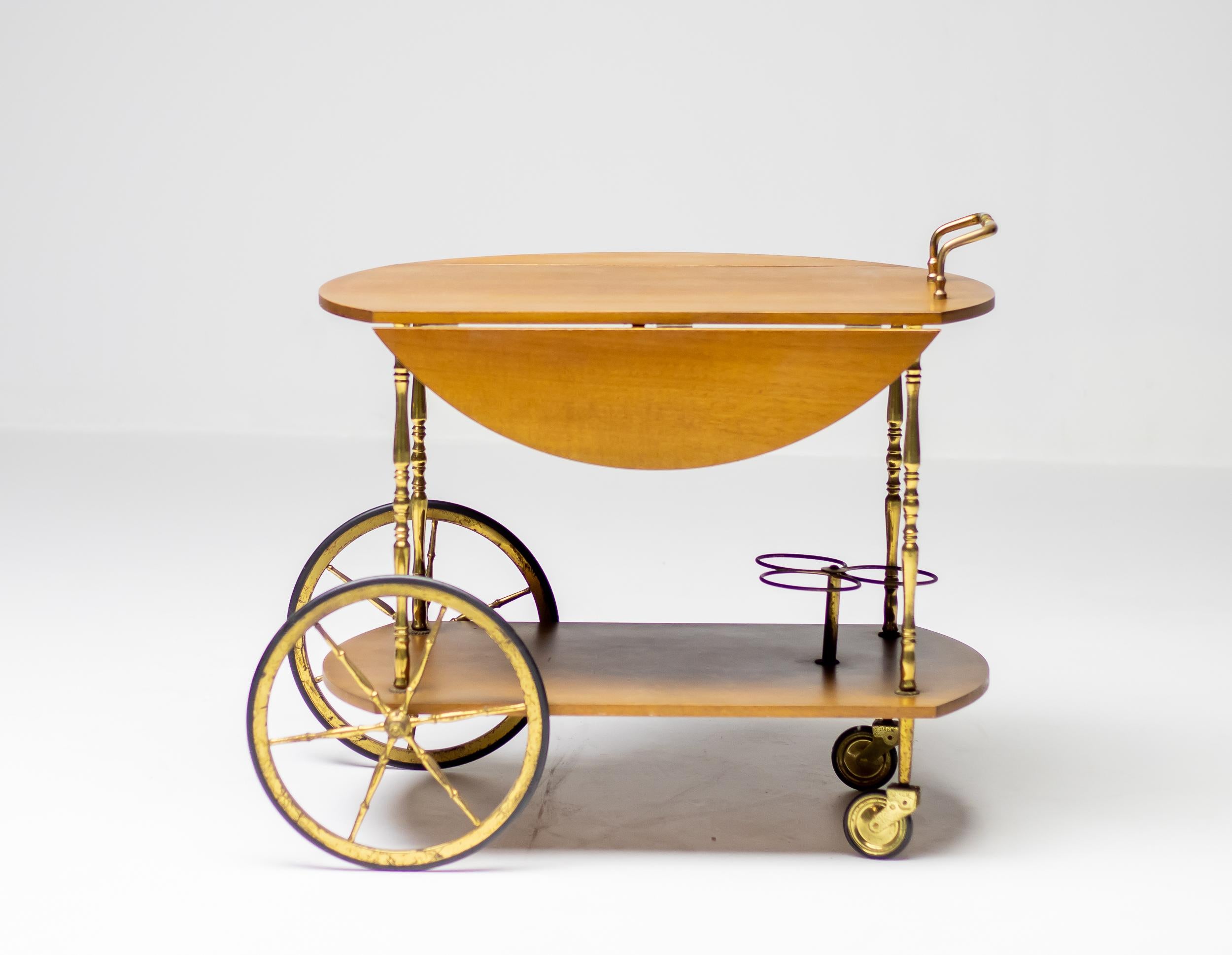 Elegant and practical bar cart attributed to Cesare Lacca, made in Italy, circa 1965. Round walnut drop down top, handles and wheels in brass. The brass shows beautiful age related patina, the walnut top and shelves are in wonderful original