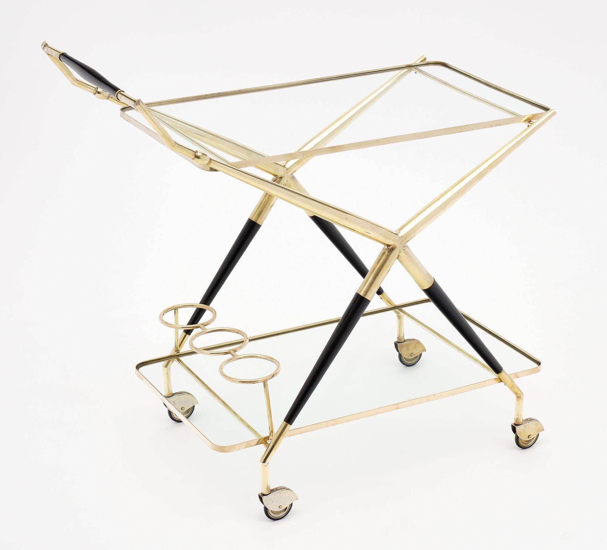 Bar cart by Italian designer Cesare Lacca featuring a solid polished brass and wood structure with original casters. There are two glass shelves and three bottle holders. This is a distinguished companion at cocktail hour!
