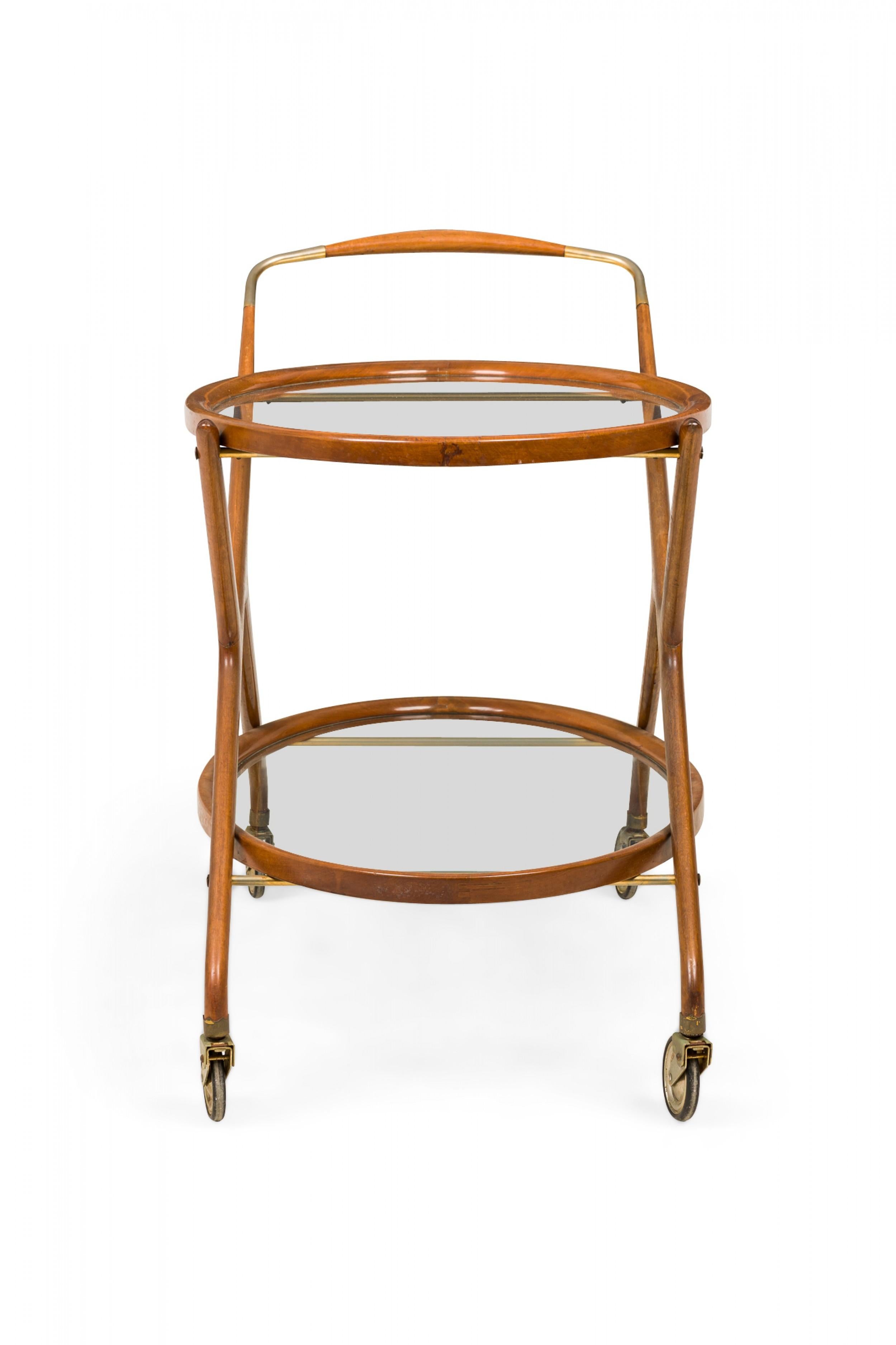 Italian Mid-Century oval form serving trolley / tea cart with a teak frame, two inset glass shelves, and a brass handle and support rods, resting on four casters. (CESARE LACCA).