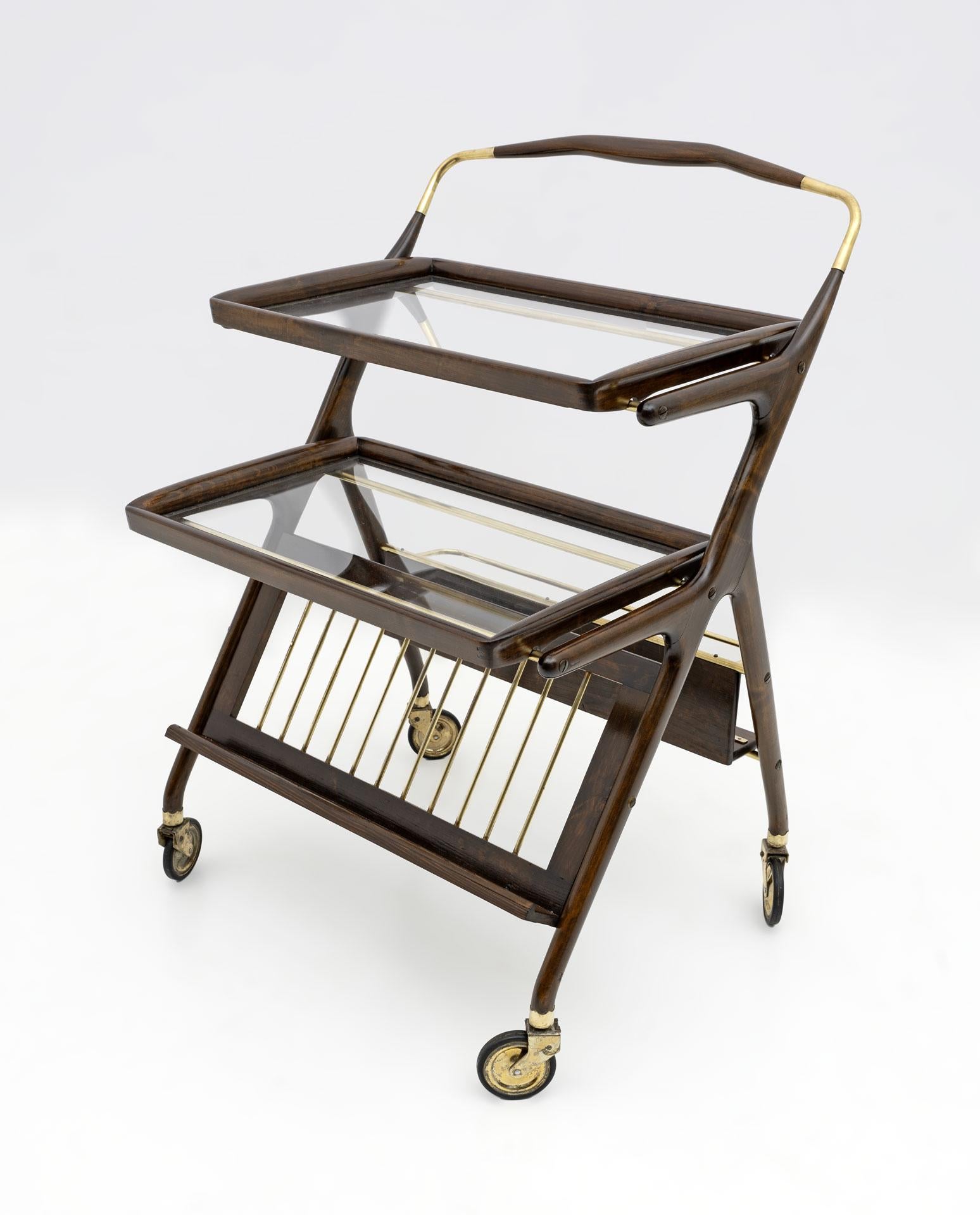 Ce chariot de bar en noyer et laiton a été conçu par Cesar Lacca pour Cassina dans les années 1950. Il est doté de deux plateaux amovibles et d'une tablette inférieure avant et arrière pour les bouteilles.
Entièrement restauré et poli à la
