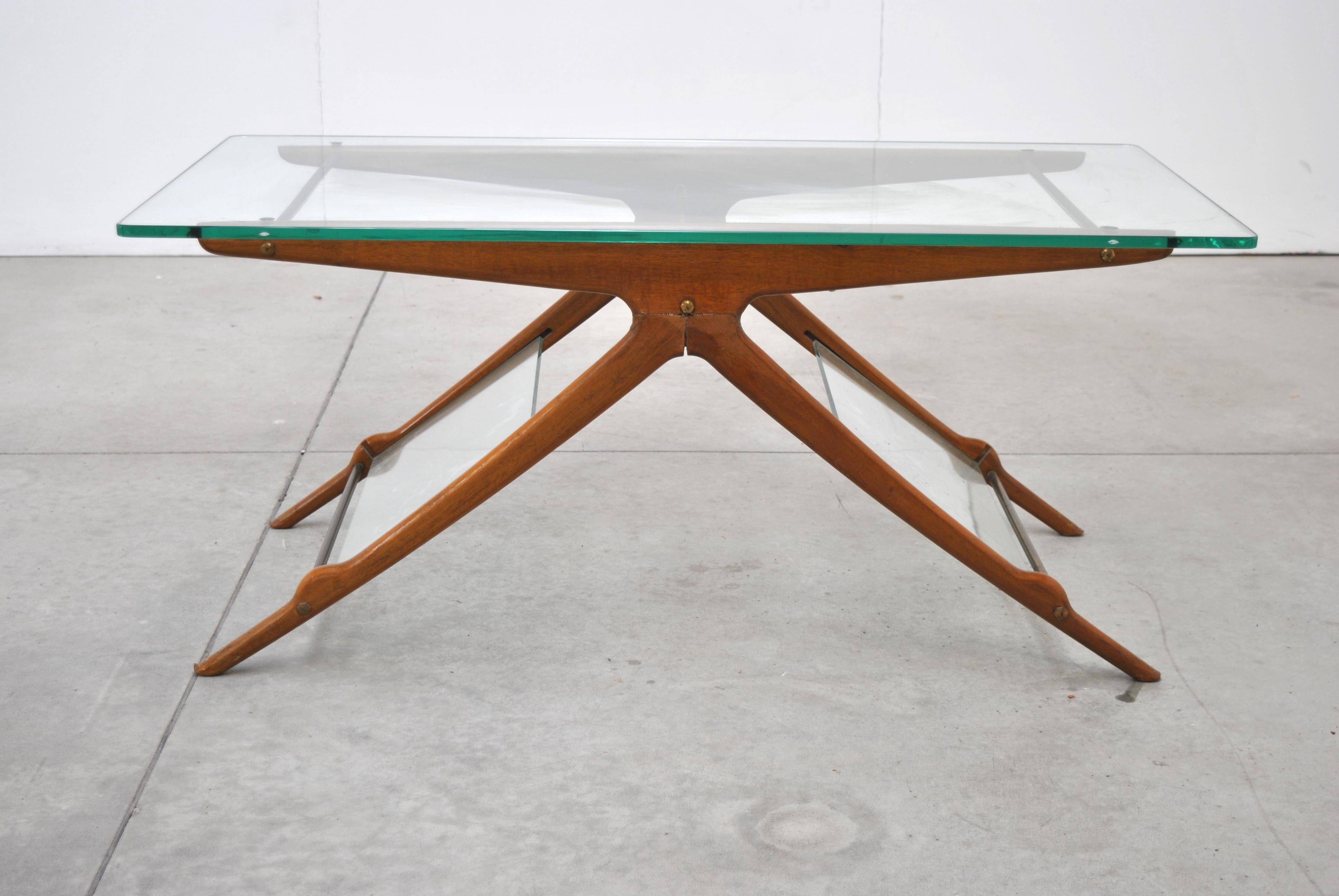 This coffee table was designed by Cesare Lacca in Italy in the 1950s. The wooden structure has the shape of a spread T.
Glass plates have been inserted between the pairs of legs to serve as magazine holders. The tabletop is also made of glass and