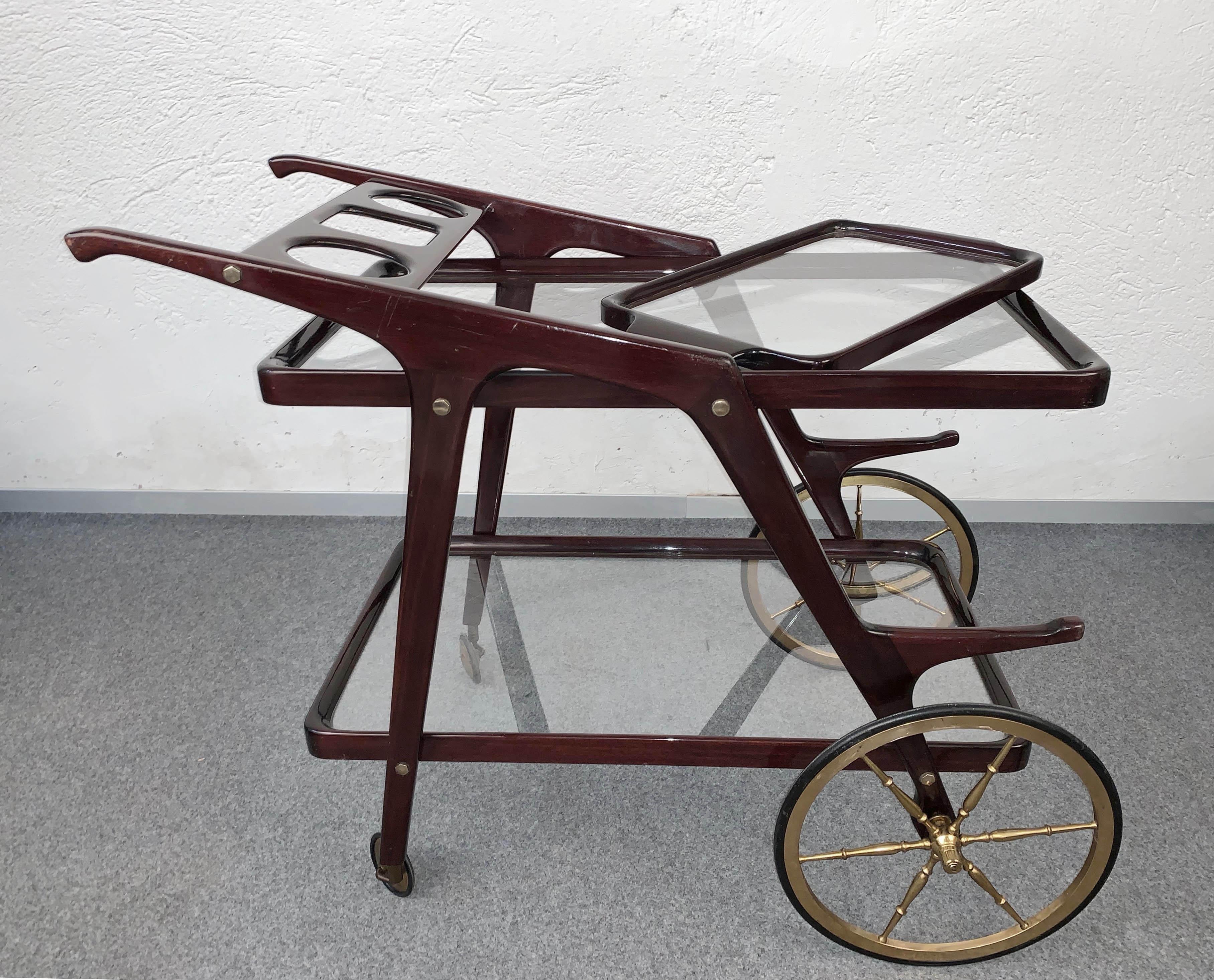 Fantastic midcentury wood bar cart with glass serving trays. This piece is attributed to Cesare Lacca and it was designed in Italy during 1950s.

This wonderful piece comes with a removable glass tray and has an ergonomic bottle holder, while the