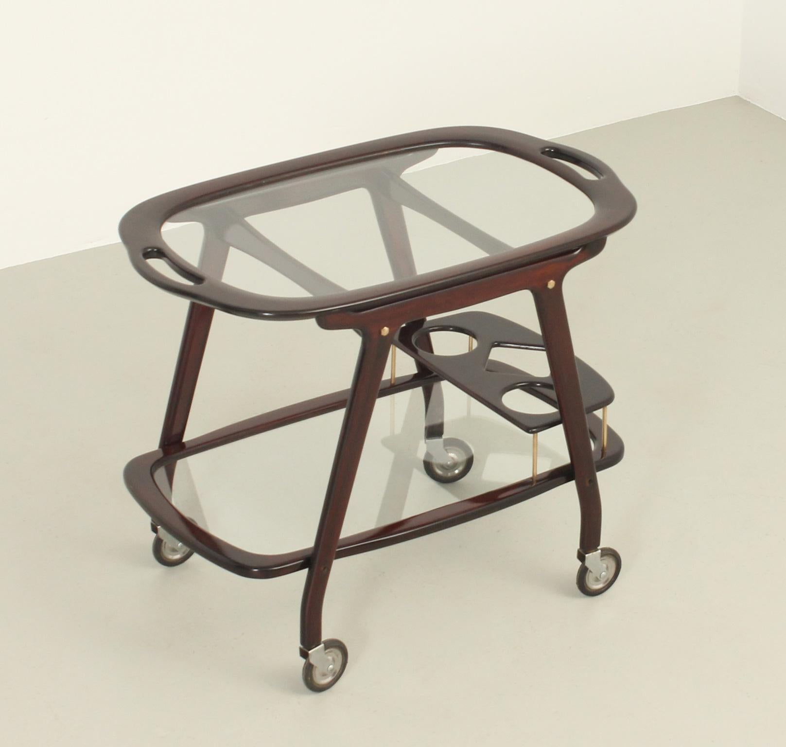 Serving bar cart designed in 1950's by Cesare Lacca, Italy. Hardwood, clear glass and brass details. Movable serving tray on top and lower shelf with bottle compartment.