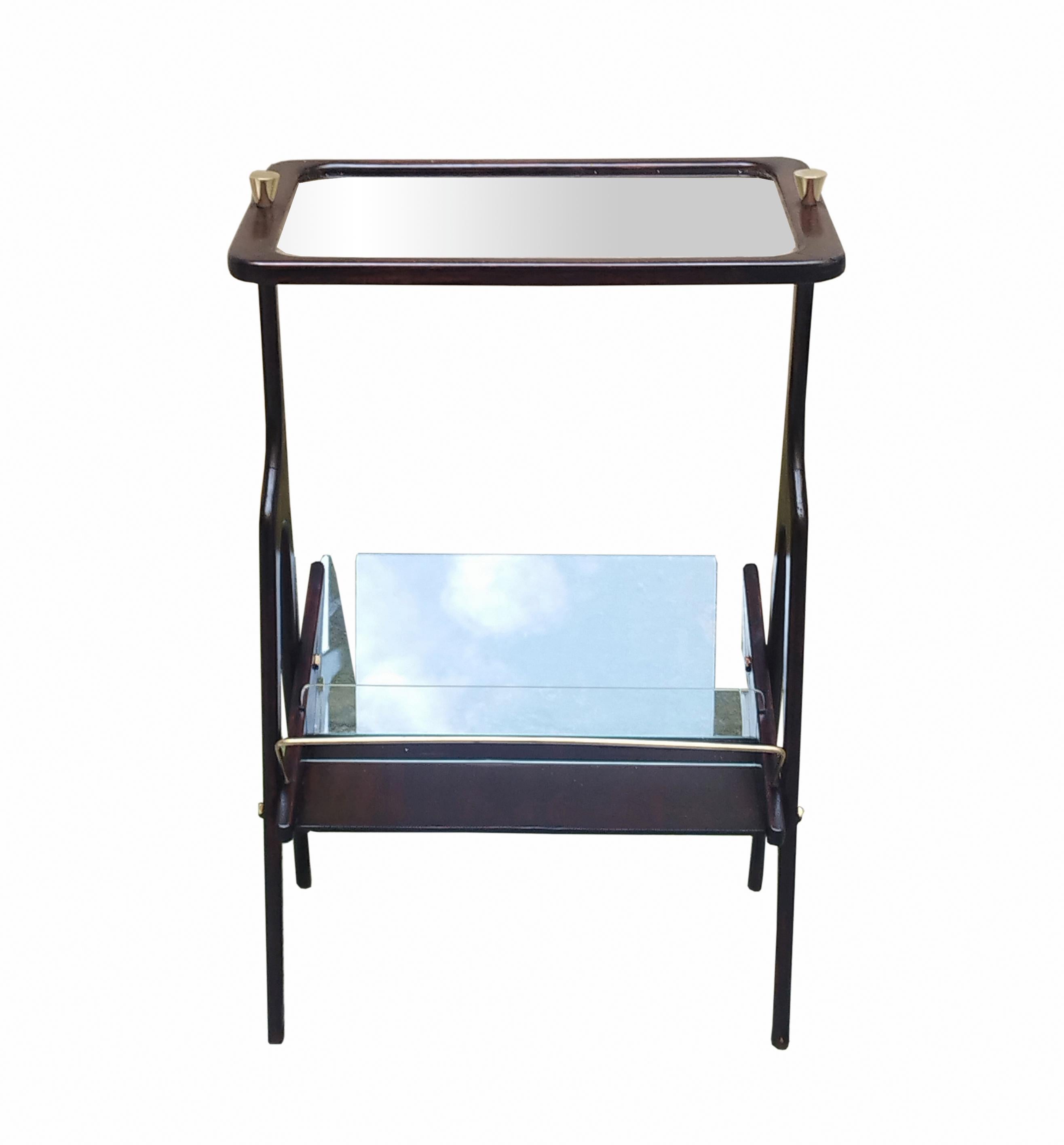 Beautiful coffee table with magazine shelf, designed by Cesare Lacca and made in Italy around 1950. This beautiful piece is made of high-quality wood in a warm dark brown colour. It has a wooden frame and a clear glass top with two brass screws.