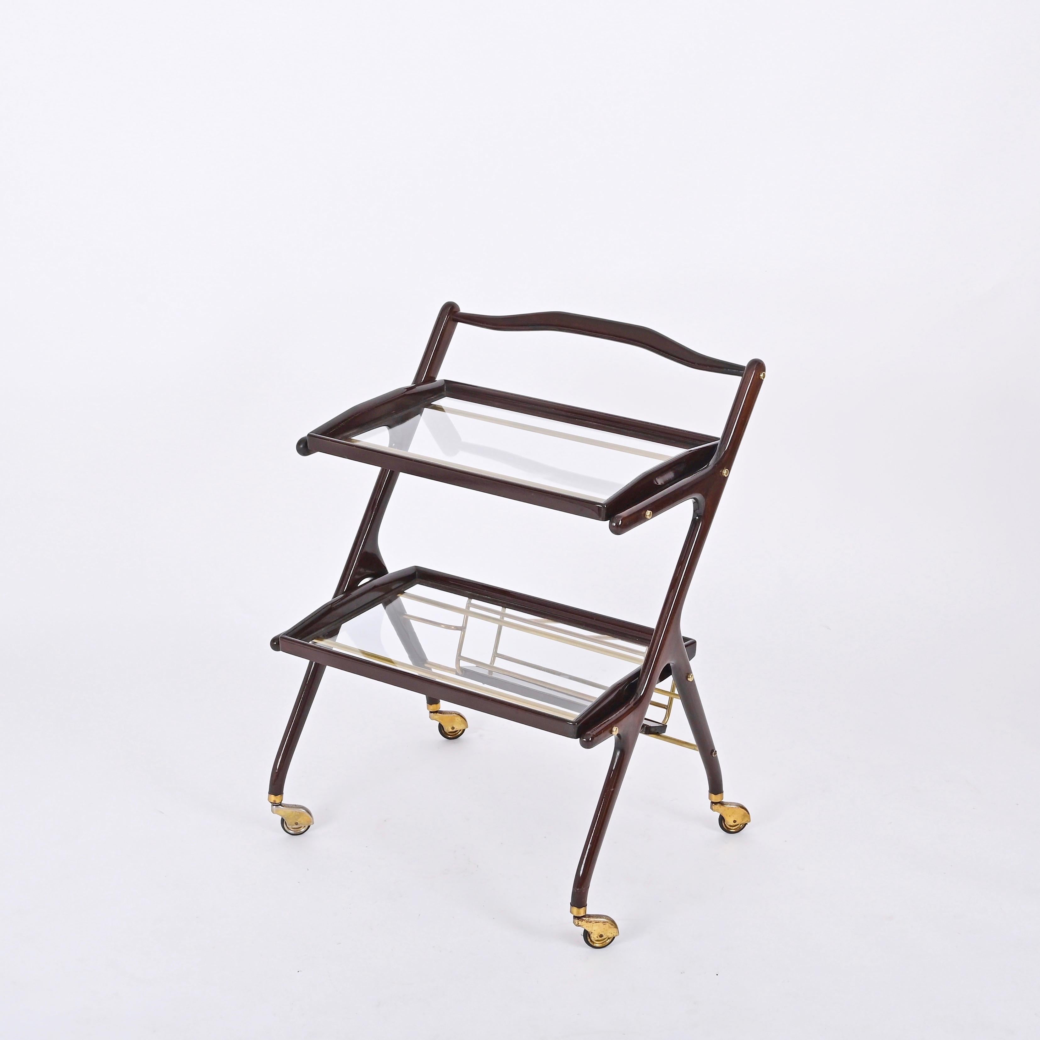 Stunning midcentury bar cart with bottle holder in wood and brass with two removable trays in crystal glass and wood. This fantastic piece was designed by Cesare Lacca in Italy during 1950s.

This structure of this serving table is fully made in a