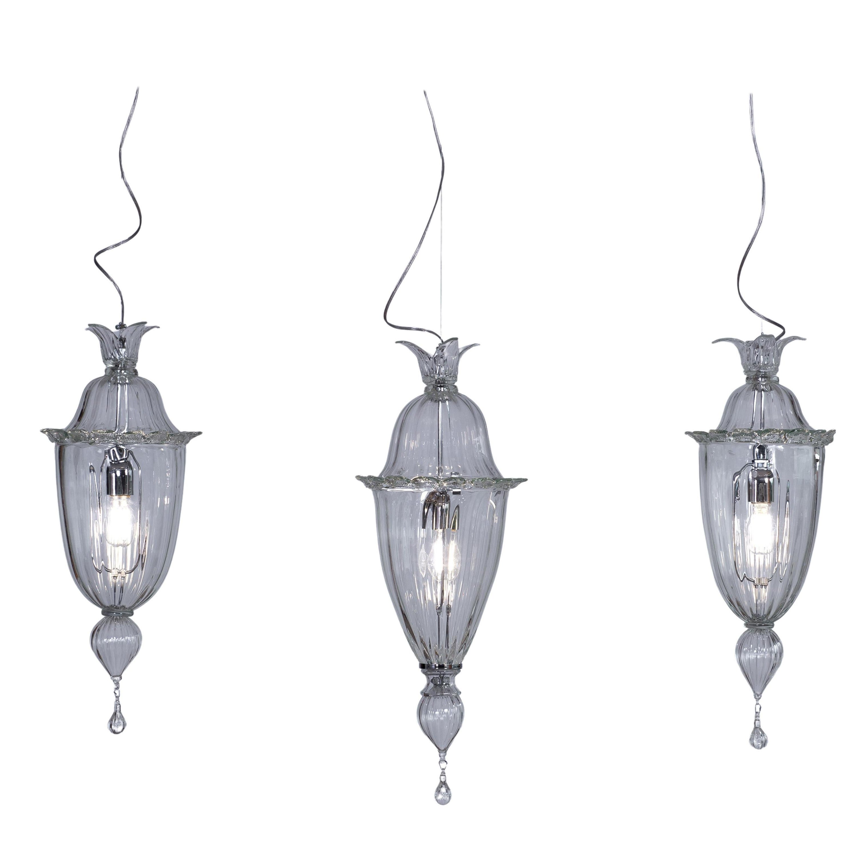 Lampadario Cesendelli in vetro di Murano trasparente moderno Italia.
Il lampadario contiene tre cesendelli trasparenti in vetro di Murano, posti a due altezze diverse e fissati al soffitto grazie a un'asta cromata lunga 51,20 pollici. Il diametro