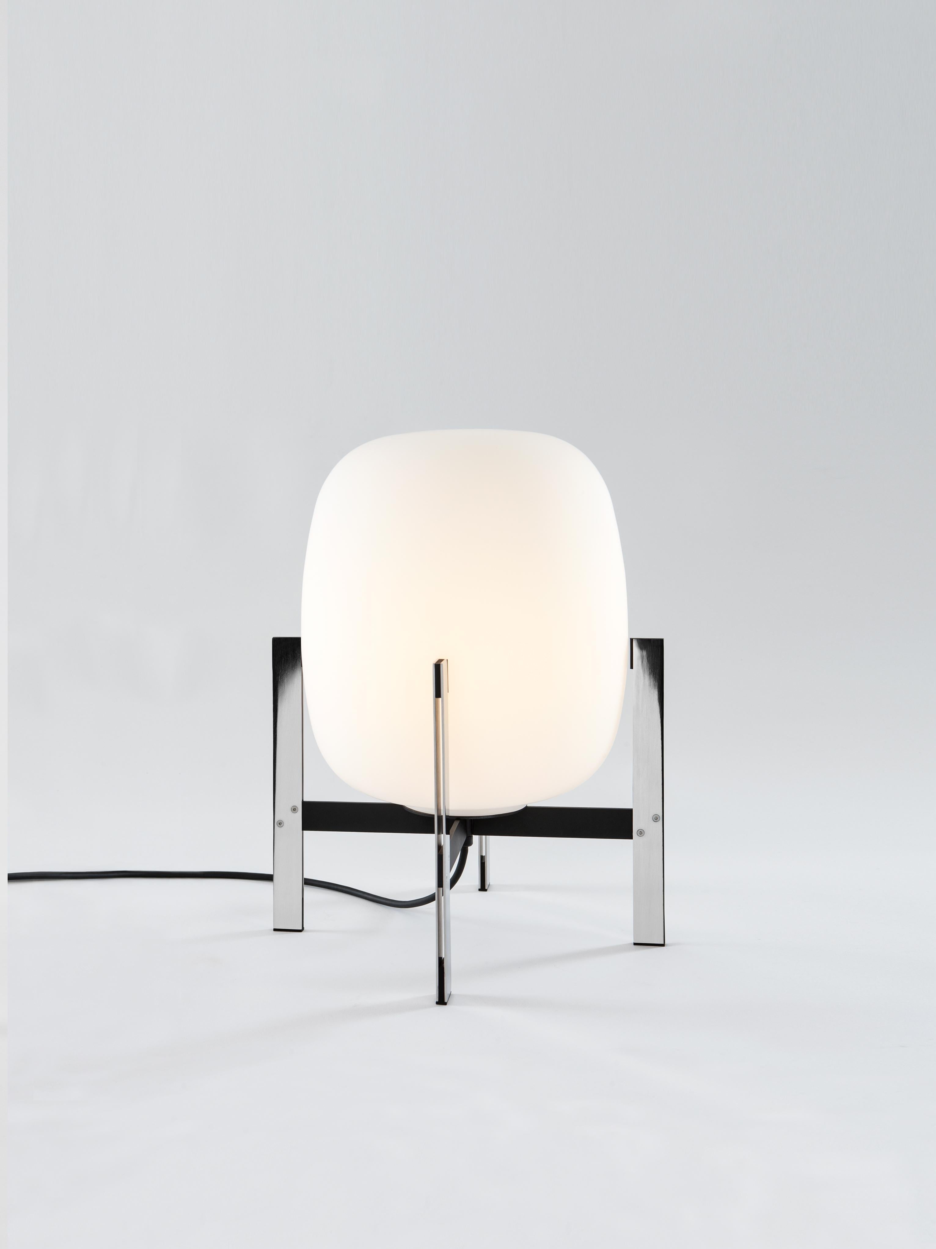 Cesta metálica table lamp by Miguel Milá
Dimensions: D 35 x H 42 cm
Materials: Steel, glass.
Available with or without leather handle.

Miguel Milá learned to master the expressiveness of steel by giving it a fragile heart. Strength and