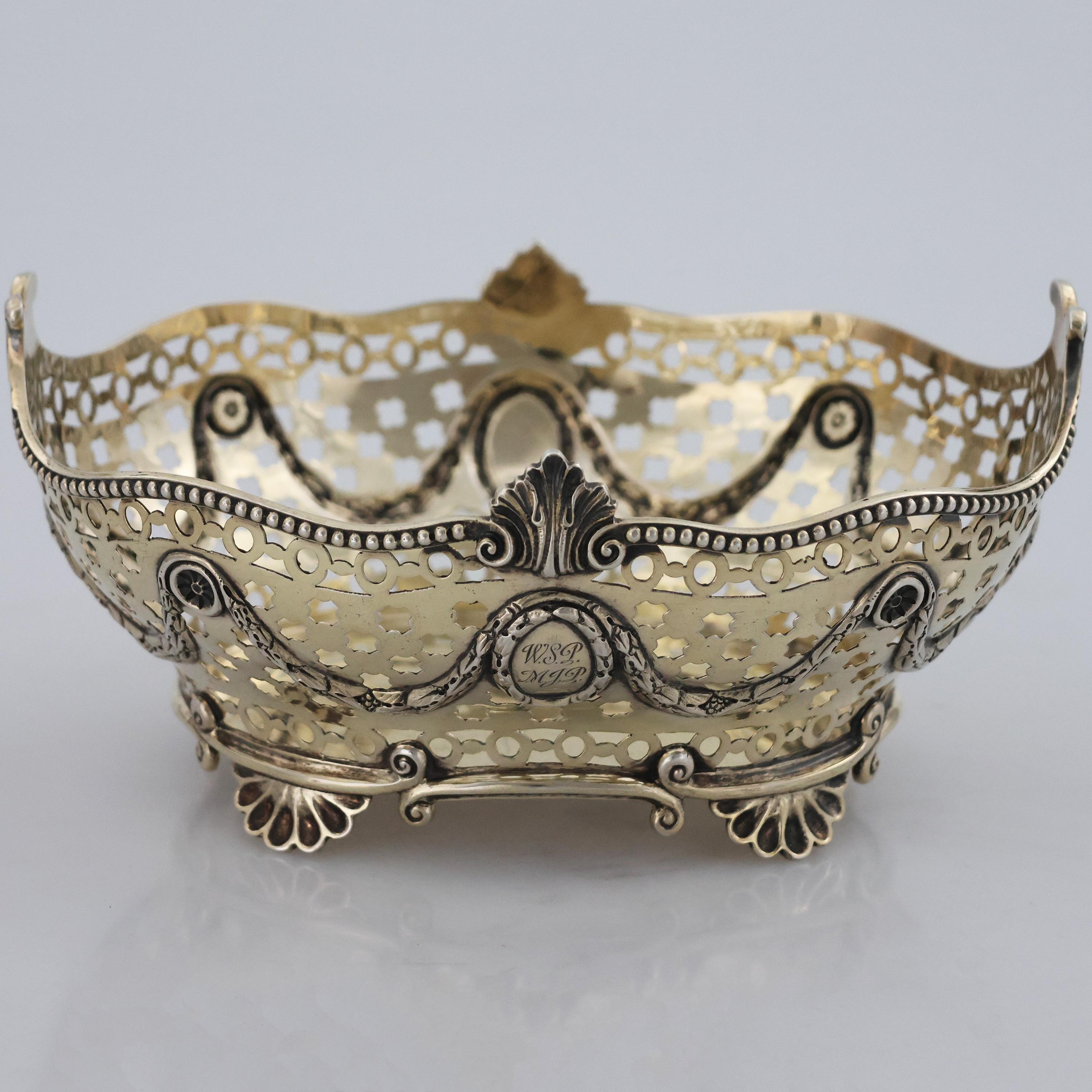 Descripción
Cesta de plata de ley y vermeil Reina Victoria, Charles Stuart Harris, Londres, 1898
Cuerpo ovalado perforado con motivos geométricos que descansa sobre cuatro pies en forma de concha.

Plata de ley marcada con 4 punzones:
Logotipo del