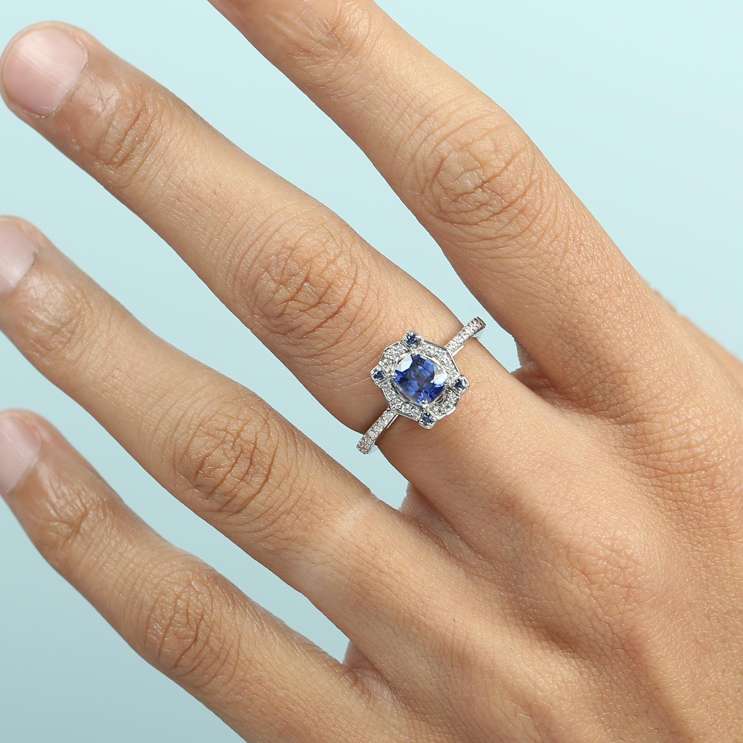 Un affascinante anello da cocktail che mette in mostra un vivido zaffiro blu di Ceylon, completato da un'aureola di diamanti incastonati per un maggiore splendore. Realizzato in oro bianco 14 carati, questo pezzo unisce un colore ricco a un'eleganza