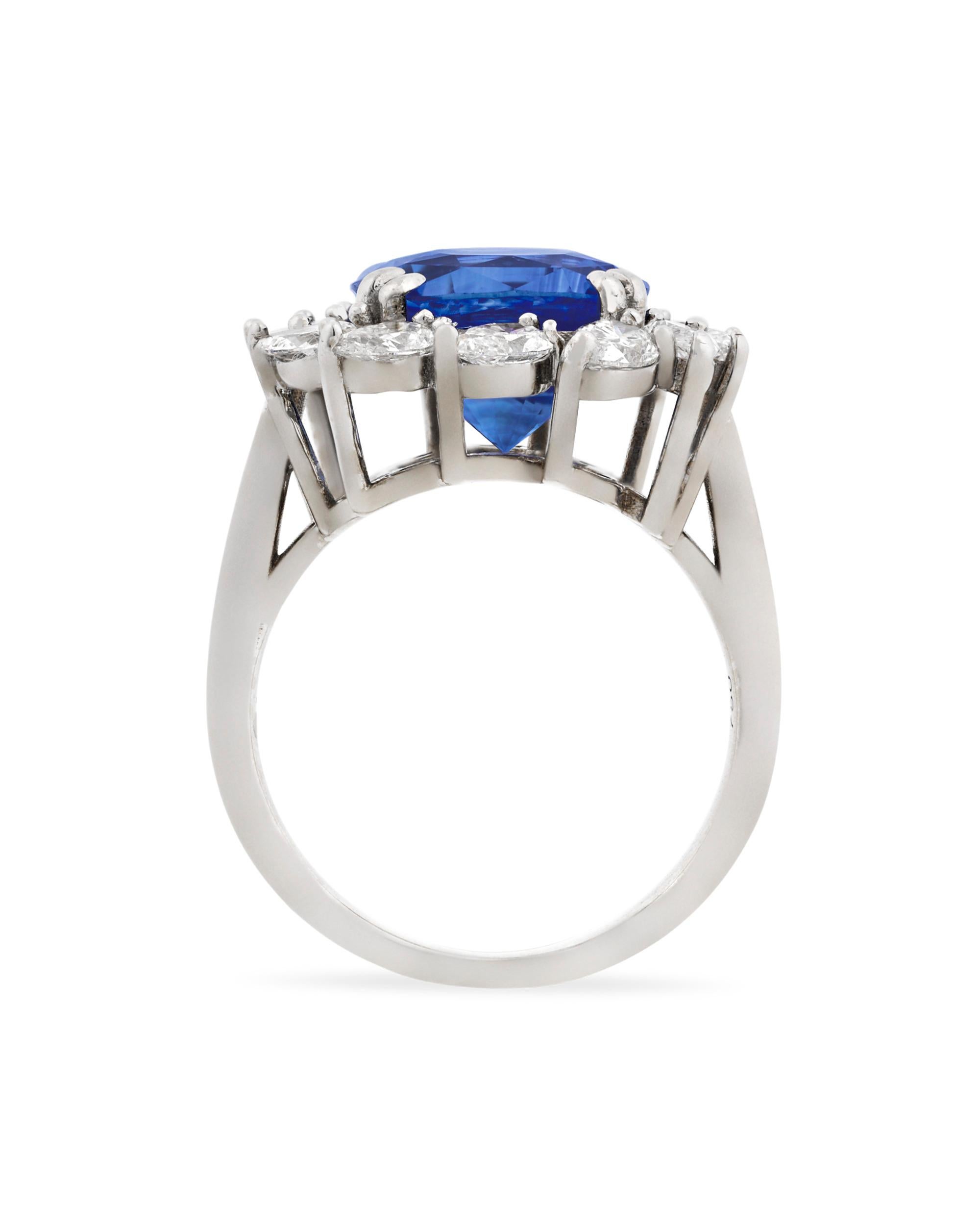 A dazzling Ceylon sapphire weighing an impressive 6.30 carats is the star of this ring. This cushion-shaped gem's rich royal blue hue is intensified by a halo of 12 pear-shaped white diamonds totaling 1.42 carats. Set in 18K white