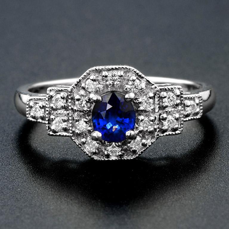 L'affascinante zaffiro blu di Ceylon ovale è incastonato con eleganza in una montatura a griffe al centro, circondato da un'abbagliante cornice di diamanti. Il design della spalla a gradini, impreziosito da altri diamanti, aggiunge un tocco di