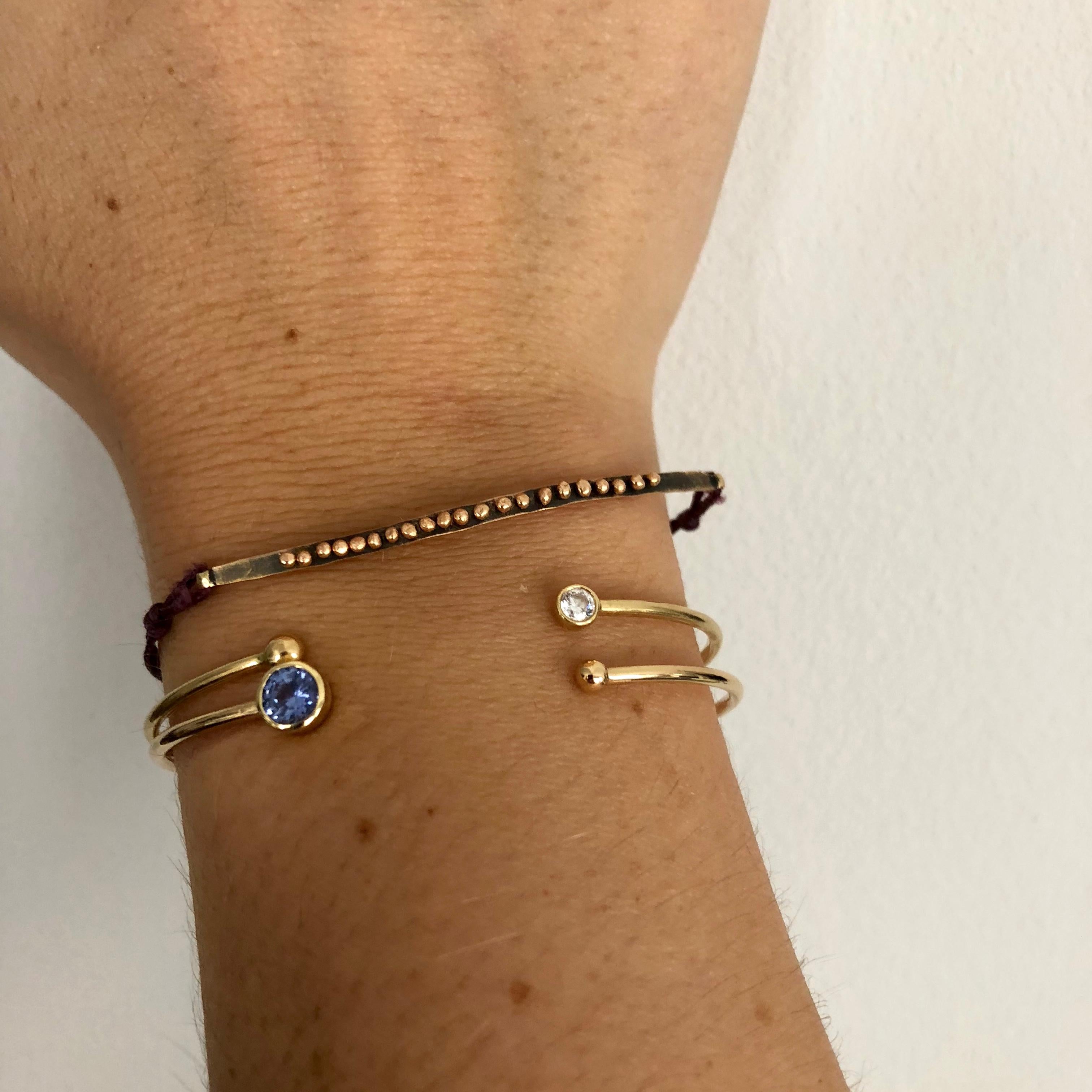 A modern gold bangle made with a 4.5mm ceylon blue Sapphire from Sri Lanka. The gold bangle fits elegantly around the wrist with a gap at the top to fit your wrist through as you put it on. A fabulous modern design for everyday wear. 

- Ceylon