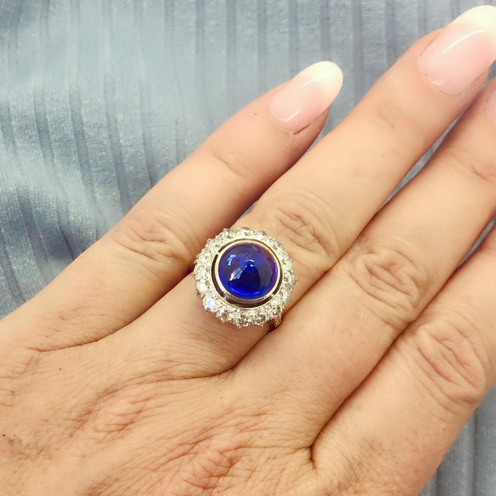 Classic and unique, this beautiful 18k gold two-tone ring features a bullet cabochon Ceylon sapphire weighing 5.52-cts, surrounded by 16 round brilliant-cut diamonds, and with diamond-set shoulders, weighing together a total of 1.57cts. The ring