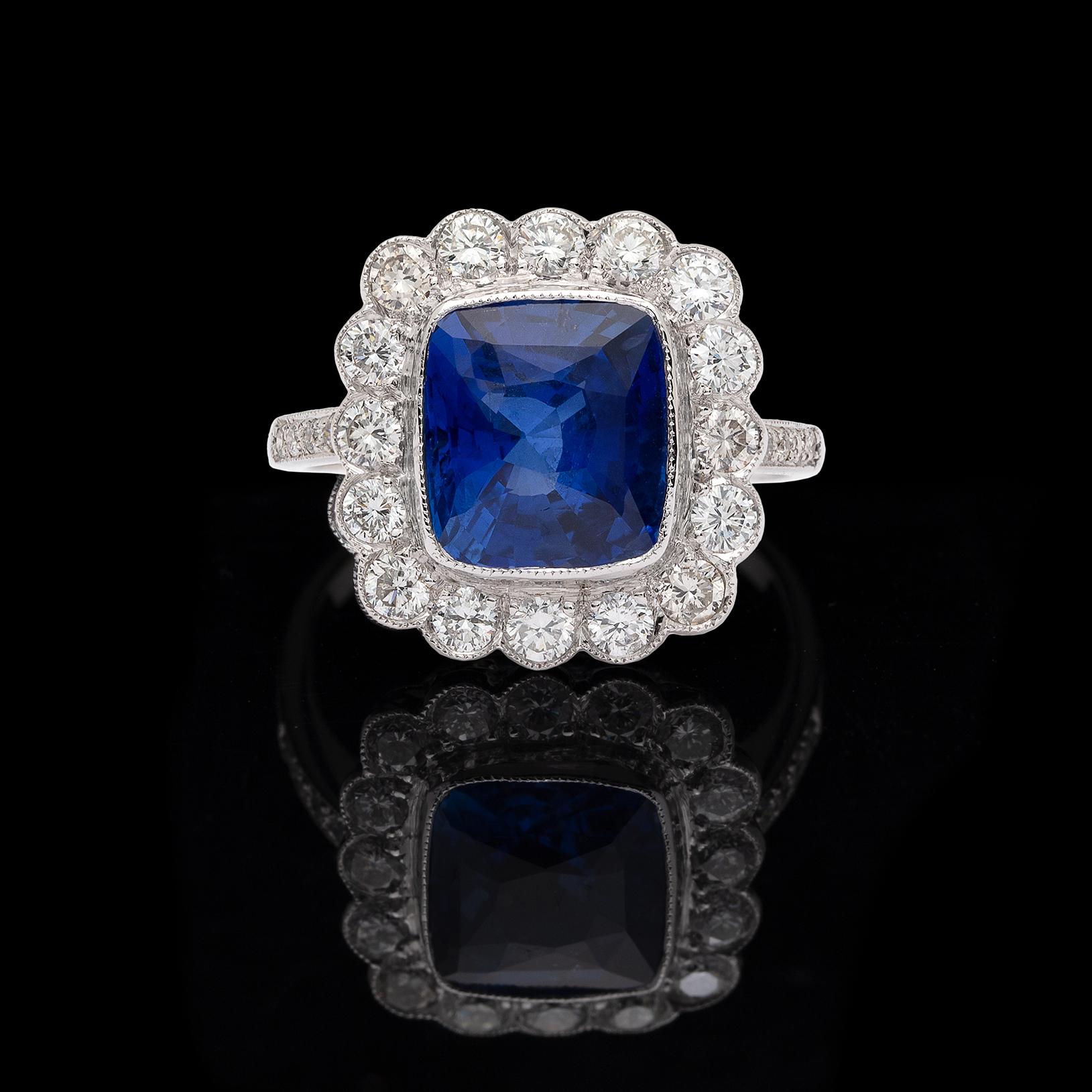 A twist on the Princess Diana design, this elegant 18k white gold ring features a 4.64-cts. cushion-cut Ceylon sapphire, bright blue and full of life, surround by 16 round brilliant-cut diamonds and with diamond-set shoulders, in total weighing