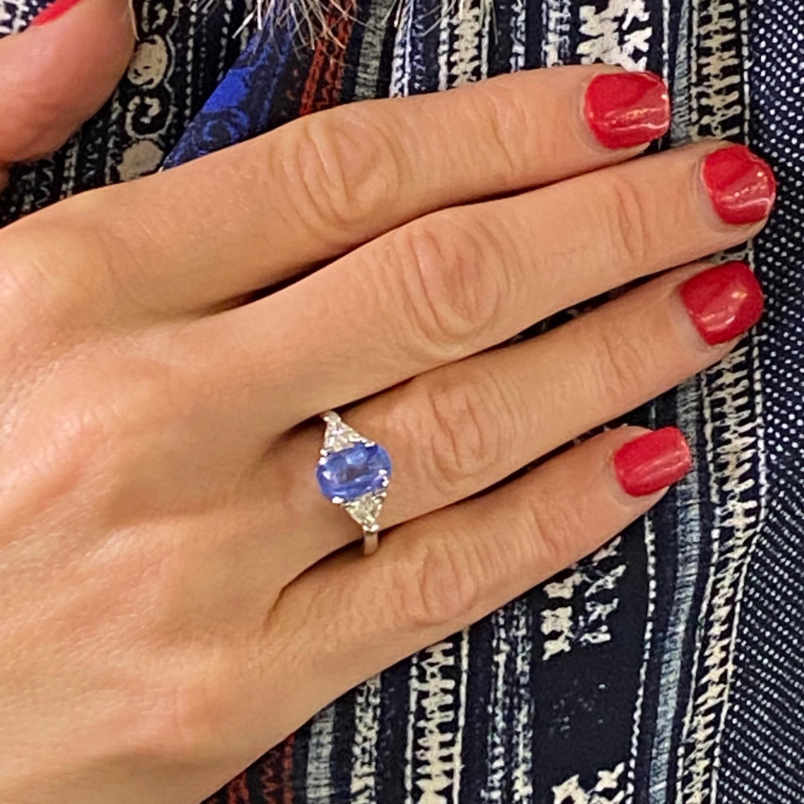 Stunning Ceylon blue sapphire diamond ring fashioned in platinum. The oval Ceylon sapphire weighs 2.50 carats and has not been treated (no heat) and is certified by the AGL. The sapphire is flanked by two trillion cut diamonds weighing .50 carat