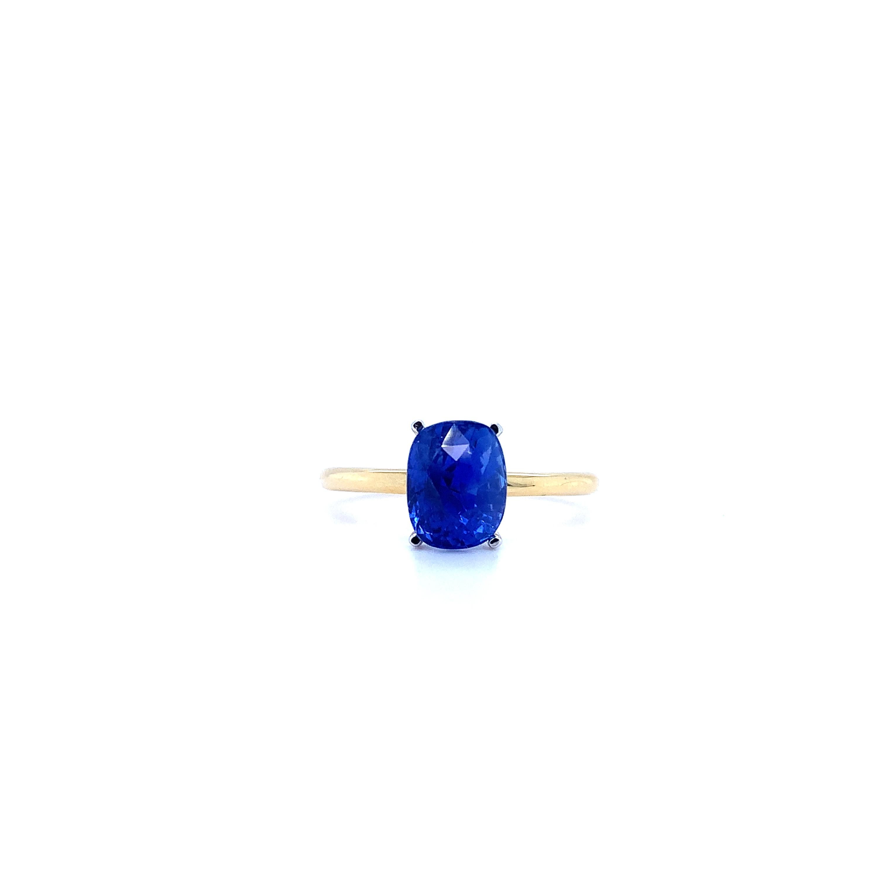 Indulge in royalty with this breathtaking 1.95ct Ceylon sapphire solitaire ring. The cushion-shaped gem is set in a classic 18k yellow gold bezel, exuding elegance and sophistication. The sapphire's regal blue hue is perfectly complemented by yellow