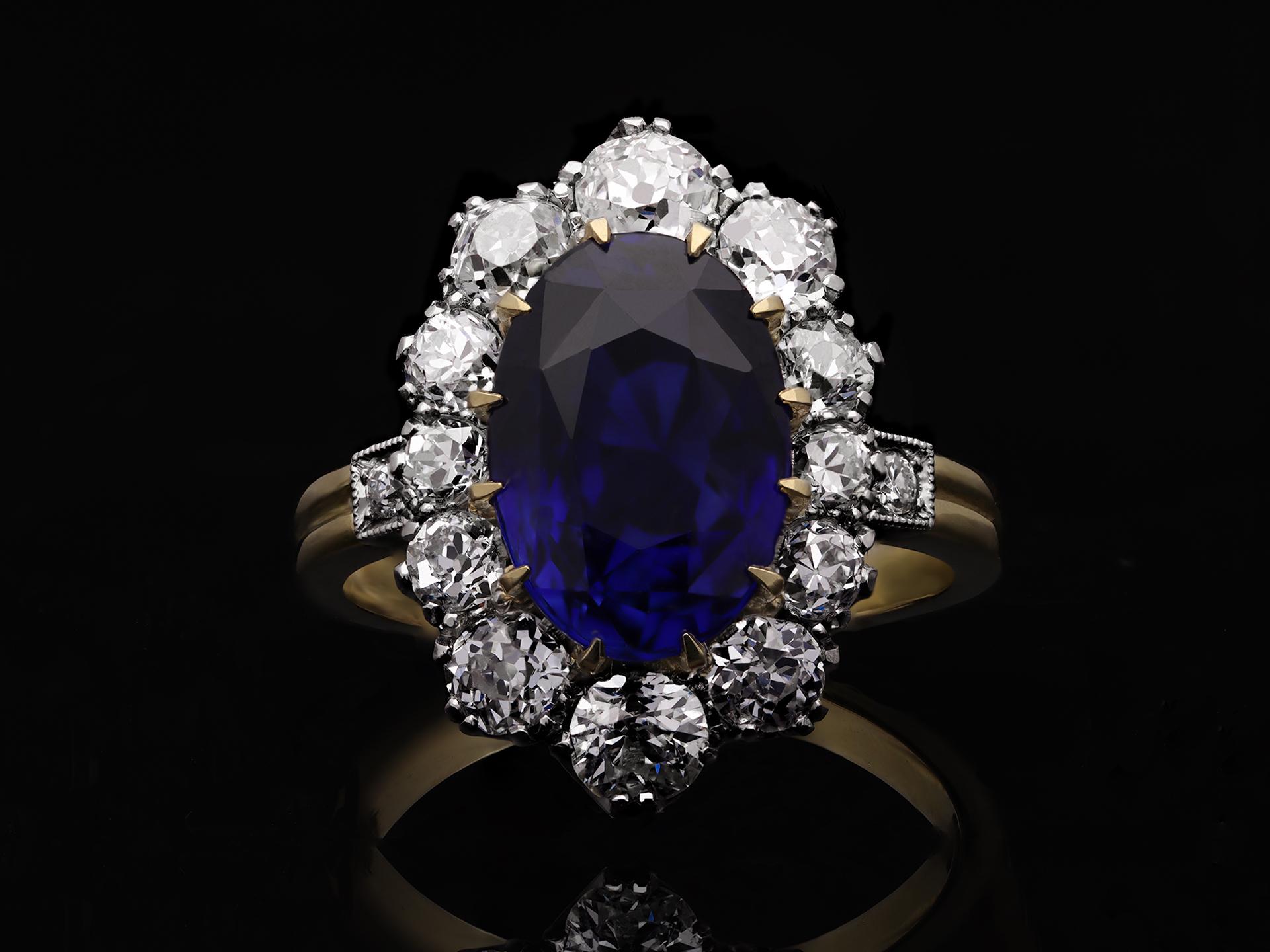 Ceylon sapphire and diamond coronet cluster ring. Set to center with an impressive oval old cut natural unenhanced sapphire in an open back claw setting with a weight of 4.764 carats, surrounded by twelve cushion shaped old mine diamonds in open