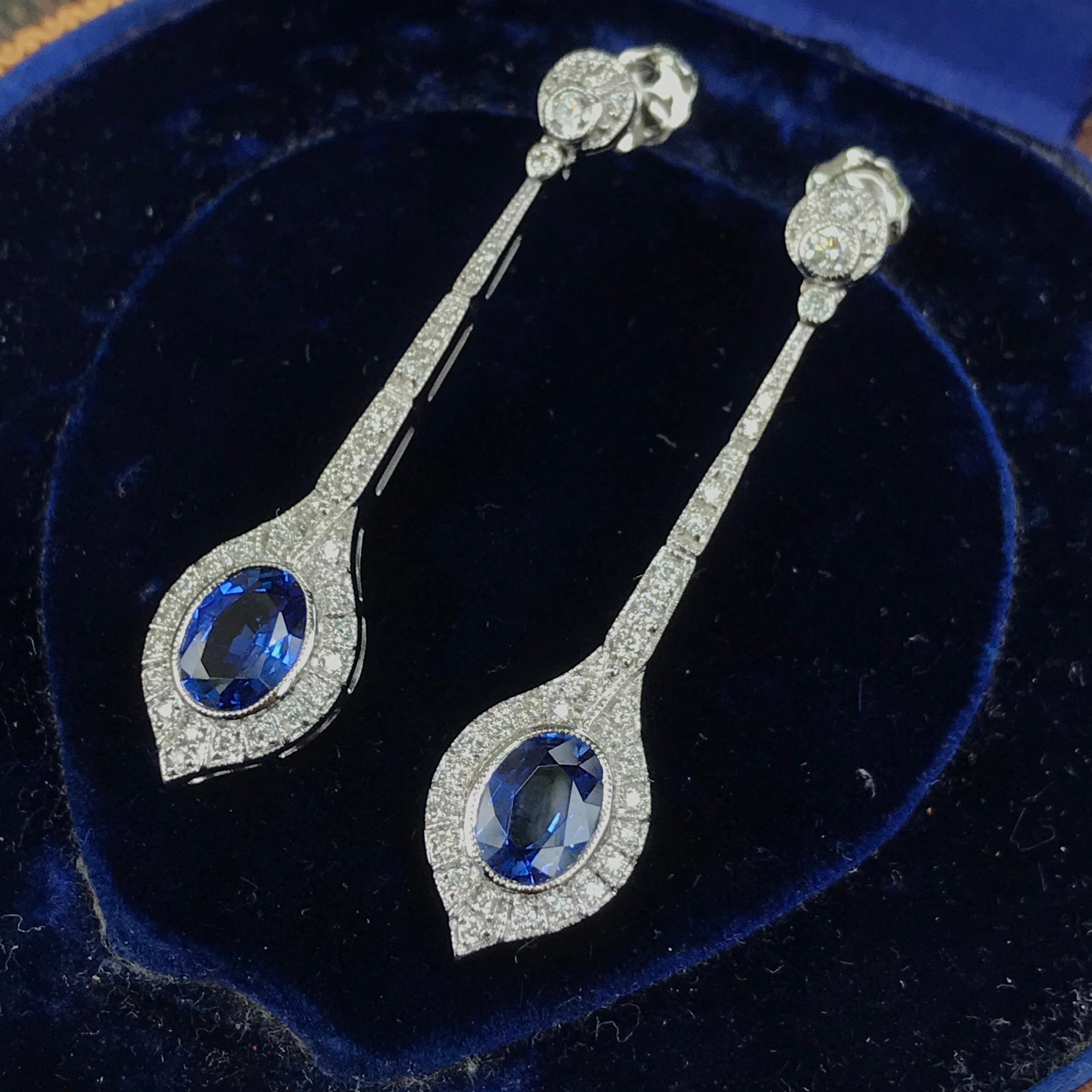 A lovely pair of long Art Deco design earrings that drop two natural cushion shape Ceylon sapphires with a total approximate gemstone weight of 3.7 carats. The earrings have an accent and line of sparkling diamonds.

Information
Metal: 18K White