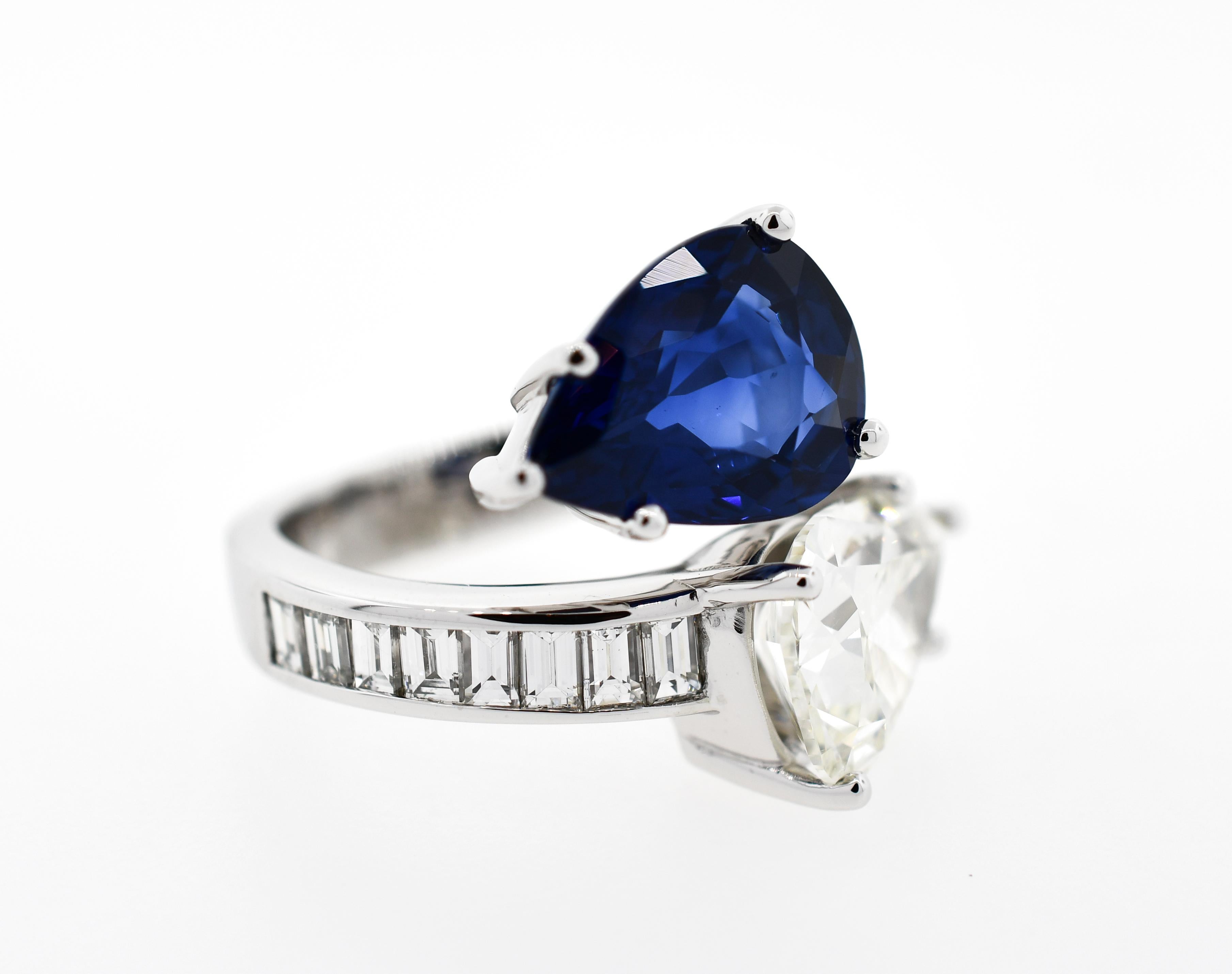 Almost 12 carats total gem weight!  Exquisitely made, custom designed platinum bypass ring featuring 1.52 carats of high quality channel set baguette cut diamonds, centered by opposing blue pear shape sapphire and pear shape diamond.  
Finger size