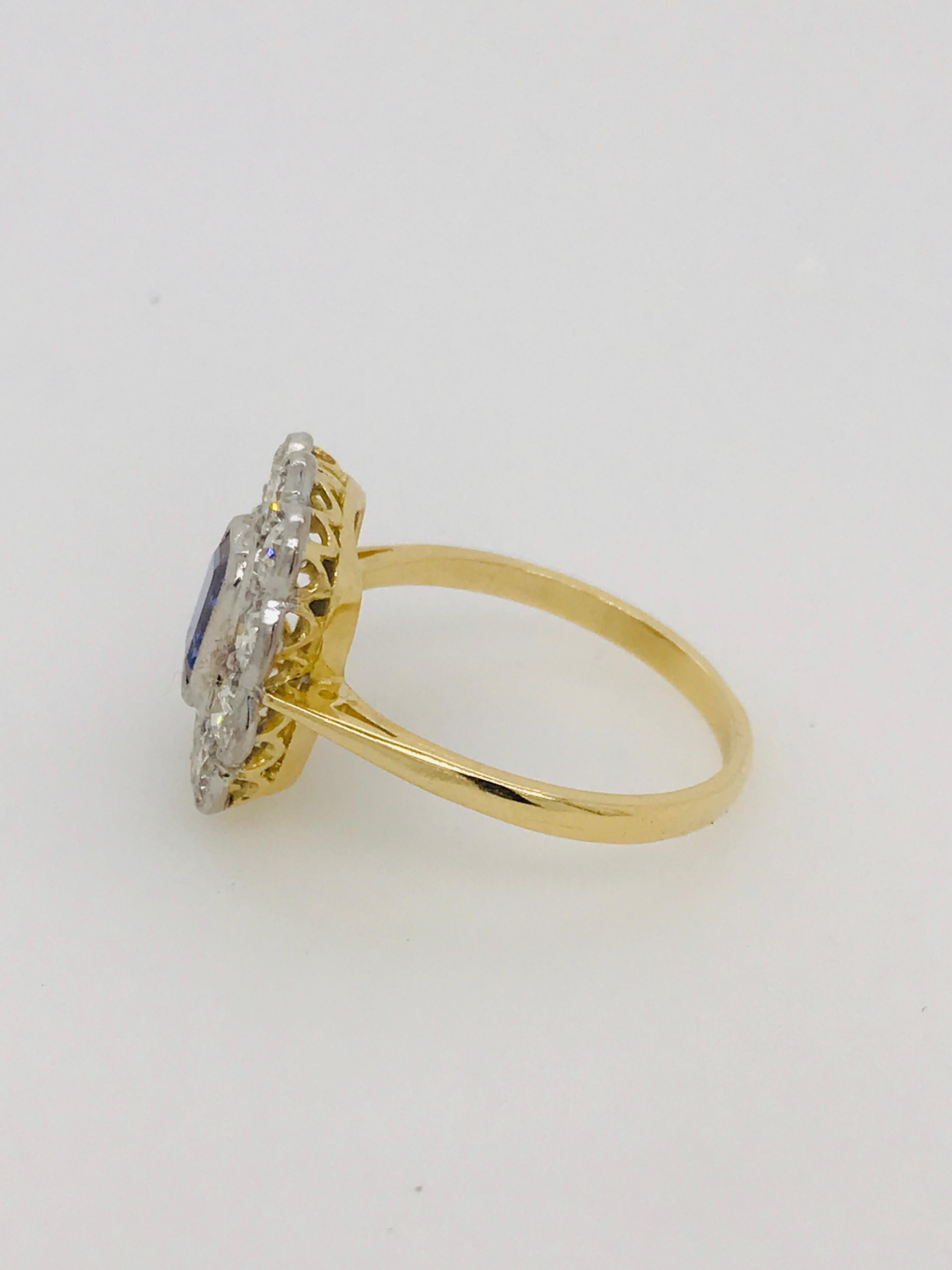 Beautiful platinum and 18ct yellow gold setting with hand pierced underbezel and set with the following - 
A Ceylon Sapphire in an emerald cut 1.18ct
Old cut diamonds in the surrounding scalloped cluster setting - 10 totalling 1.00ct HSI2
Ring size