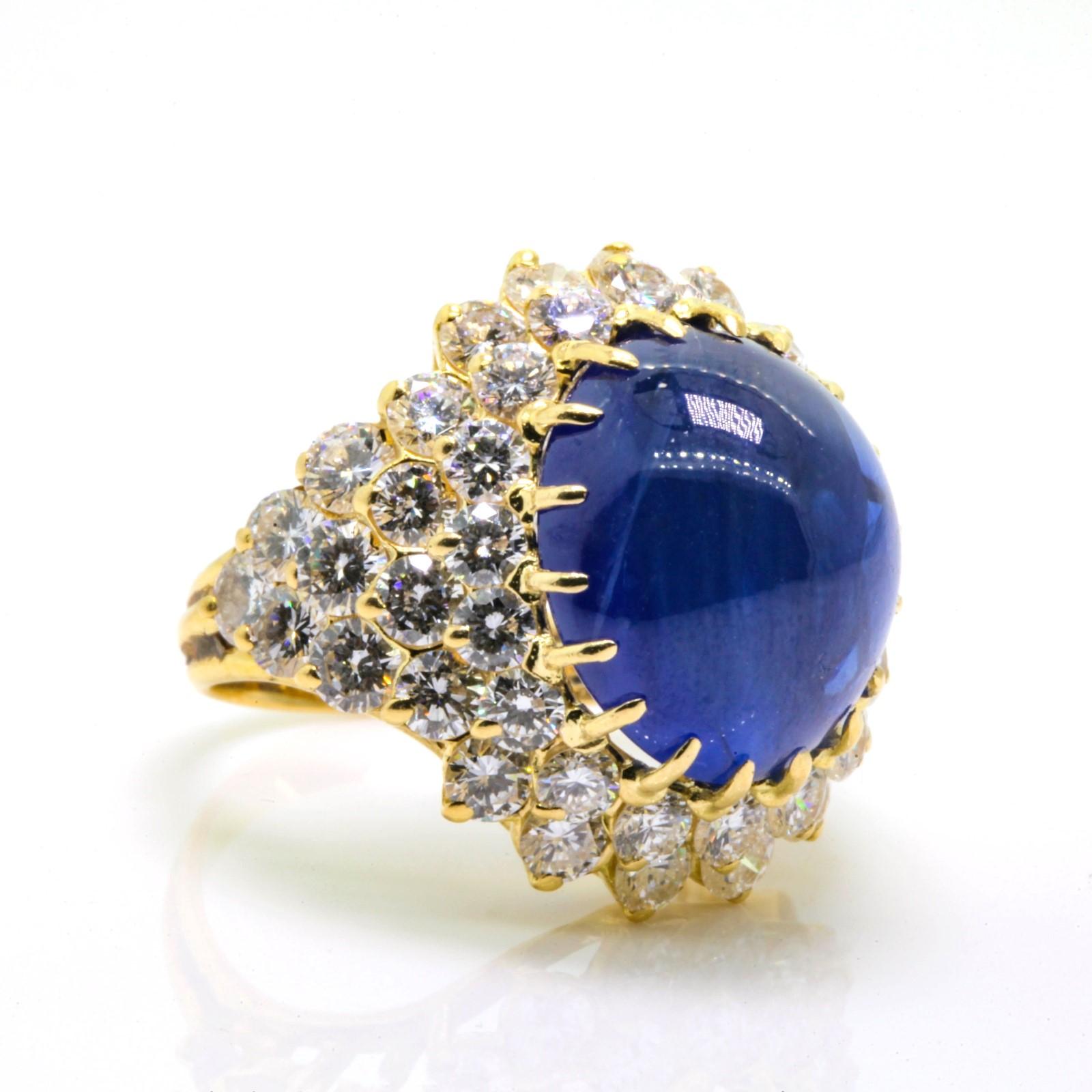 Ostentatiously perfect!   Beautifully made 18KT gold ring flaunting a 15.74 carat luminous cabochon cut Ceylon Sapphire, surrounded by 5.75 carats of shimmering  Round Brilliant Diamonds of G/H color - VS clarity.  Ring size 6.5 Circa 1970s 