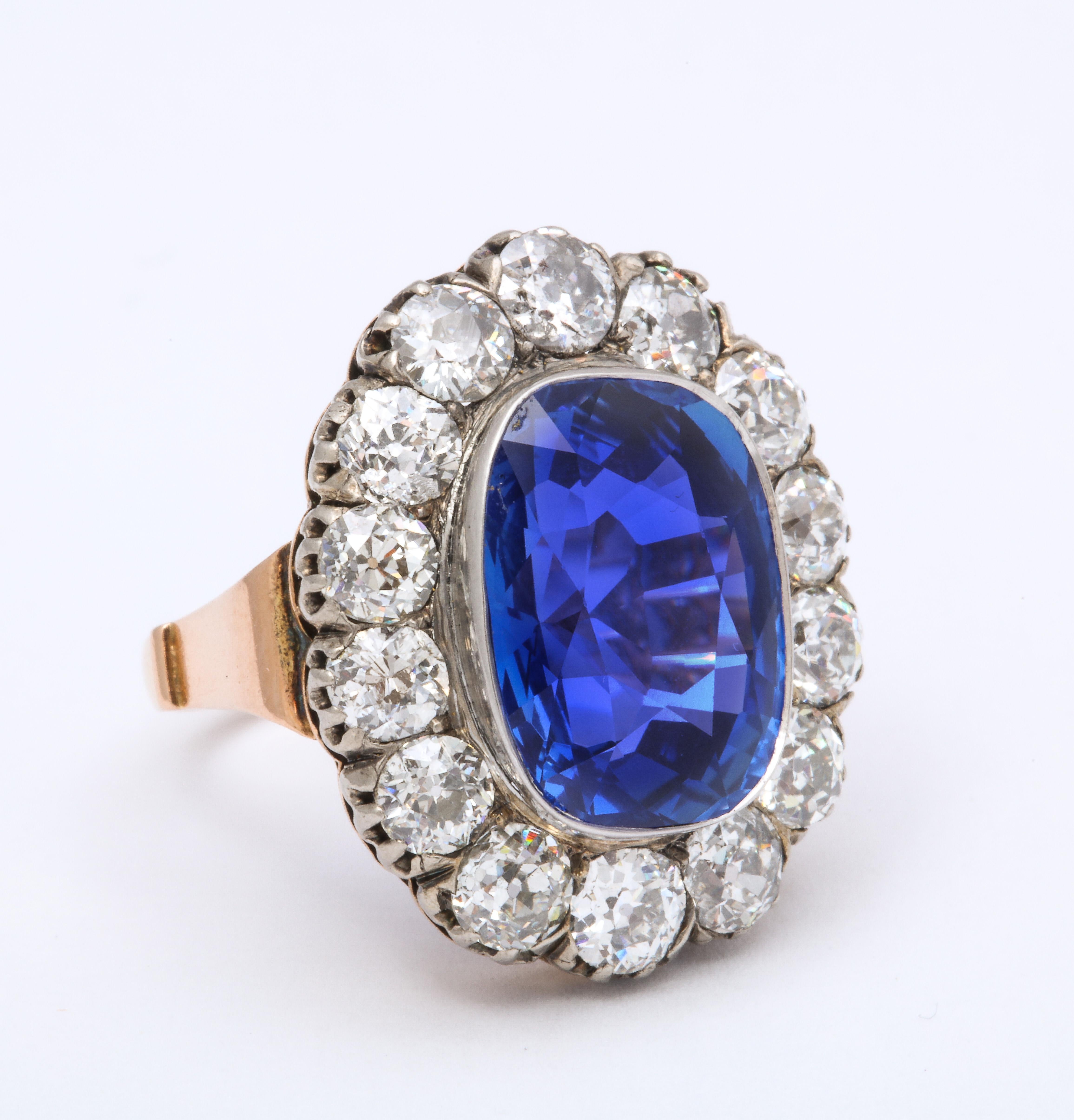 Circa 1880's Ceylon Sapphire and Diamond ring in 15k Yellow Gold, stamped KS. There are 14 old mine cut diamonds totaling 4.50 carats. The center showcases an 11.70 carat cushion cut natural Ceylon Sapphire.  Circa 1850. Size 6.  AGL report