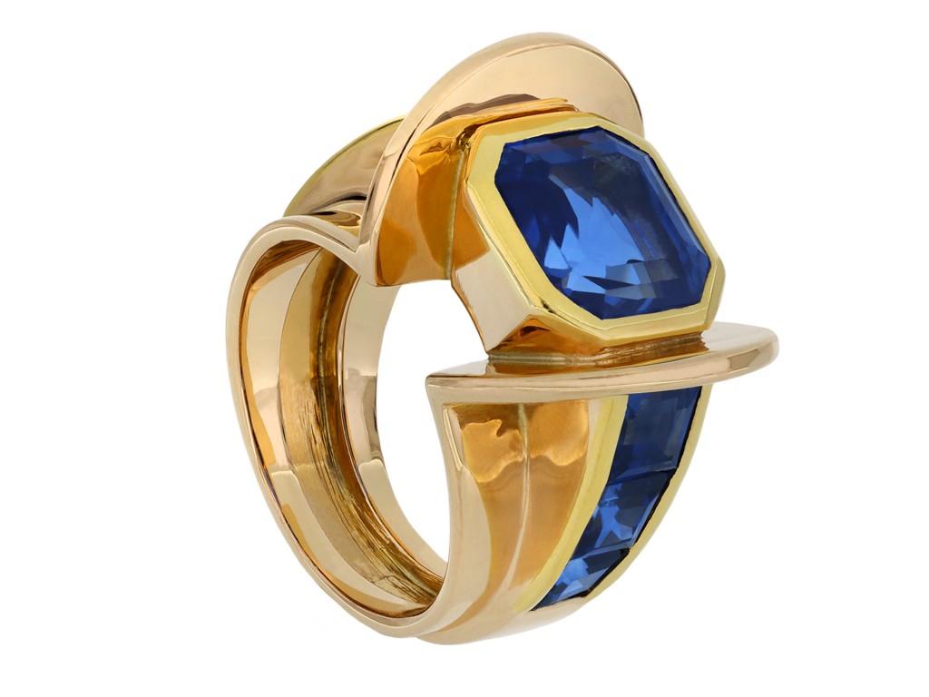 Ceylon sapphire flank solitaire ring. Set to centre with an octagonal emerald-cut natural unenhanced Ceylon sapphire in an open back rubover setting with an approximate weight of 4.20 carats, flanked by six square step cut natural unenhanced