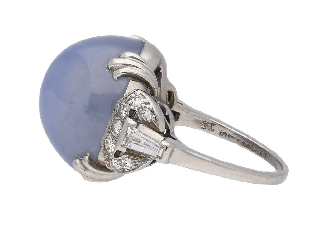 Ceylon star sapphire and diamond ring by J. Milhening. Centrally set with an oval cabochon natural unenhanced Ceylon star sapphire in an open back claw setting with an approximate weight of 30.00 carats, flanked by two tapered baguette cut diamonds