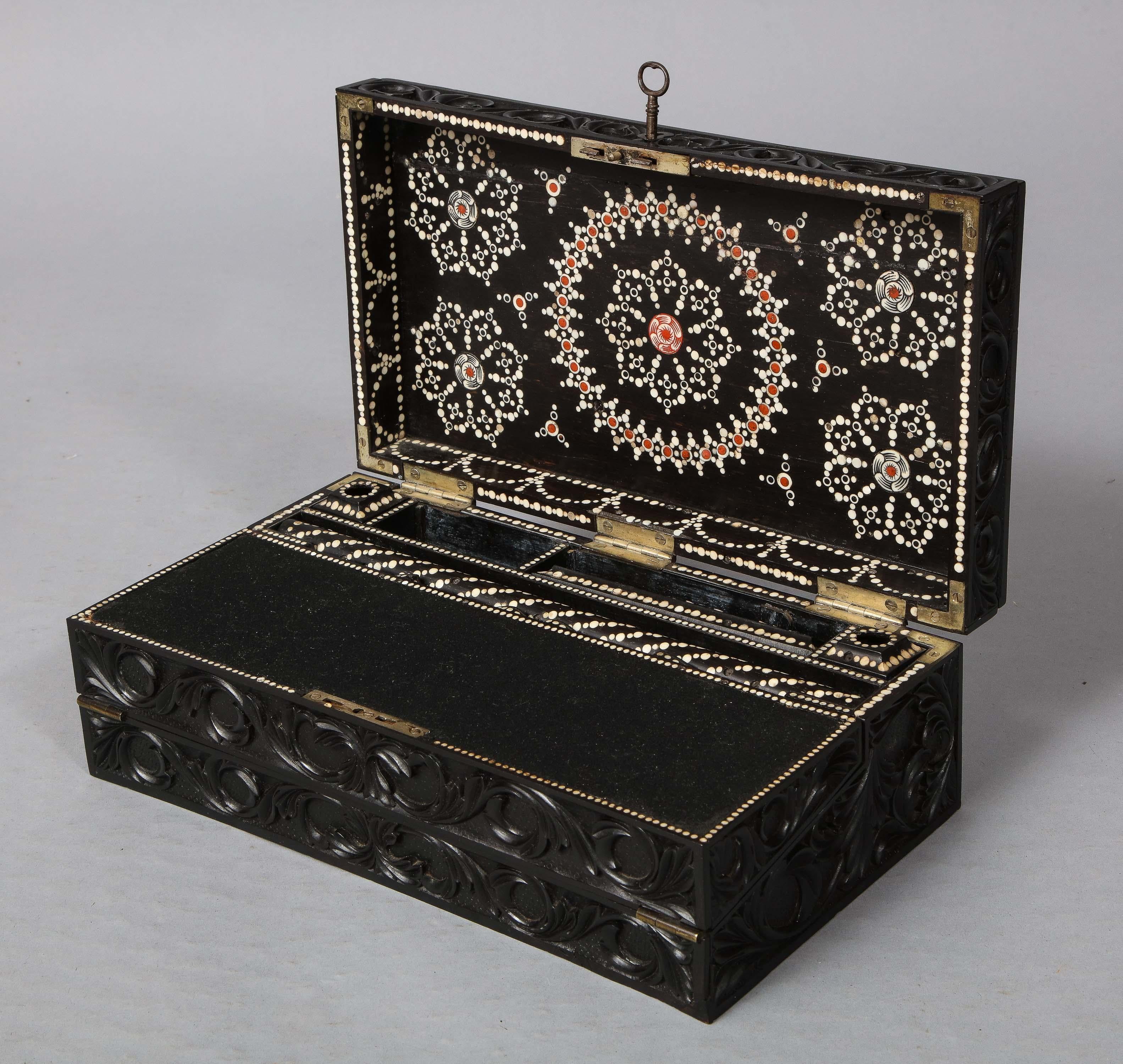 Very fine early 19th century carved ebony writing slope, the exterior richly carved with foliate decoration, the interior profusely inlaid with bone dots forming floral geometric patterns and fitted with inkwells, pen case, roller and secret spring