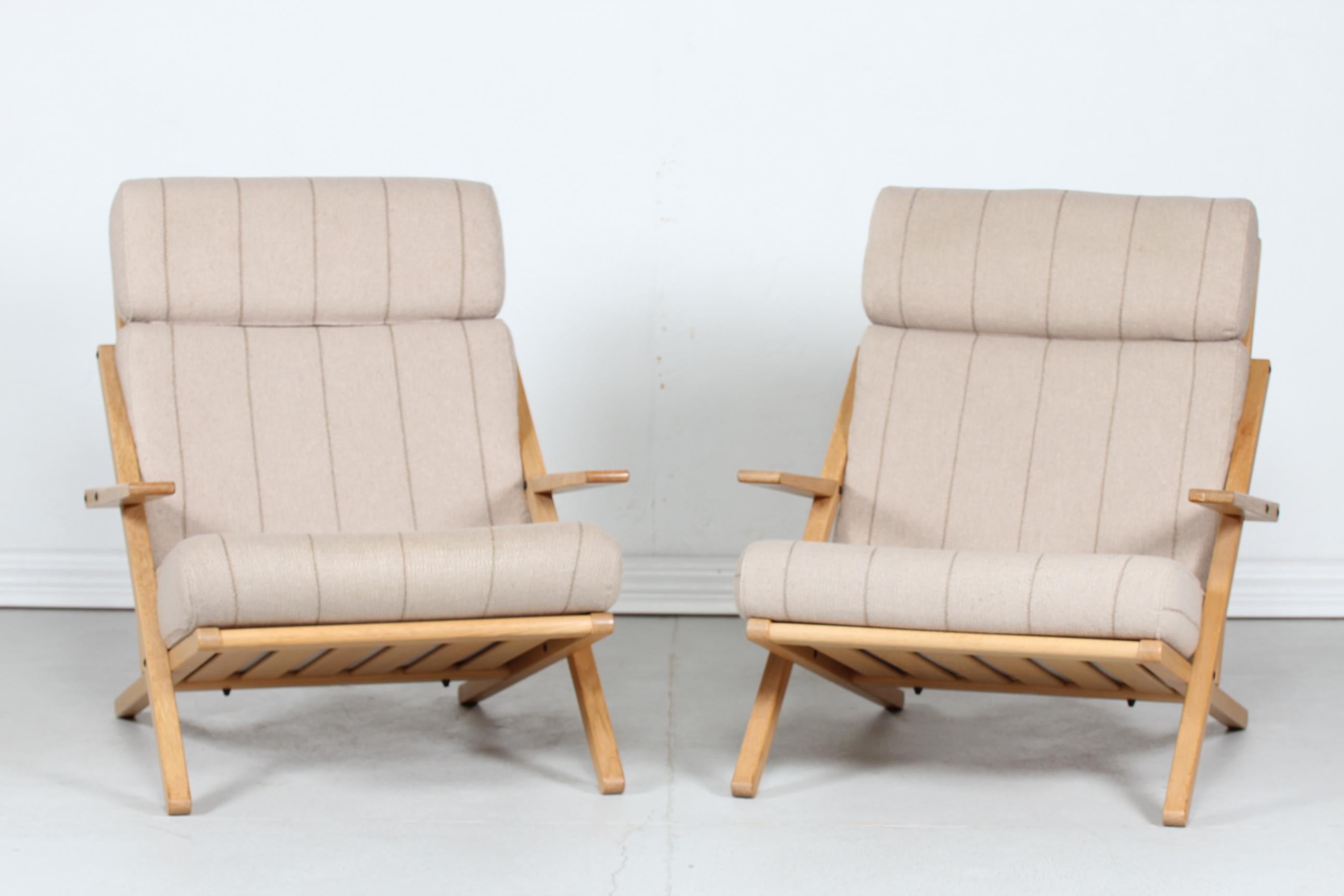 Pair of Danish modern lounge chairs or easy chairs manufactured by C. F. Christensen, Silkeborg, Denmark.
The chairs are made of solid oak. with lacquer.
Loose cushions with the original light colored fabric with stripes.

Nice vintage condition